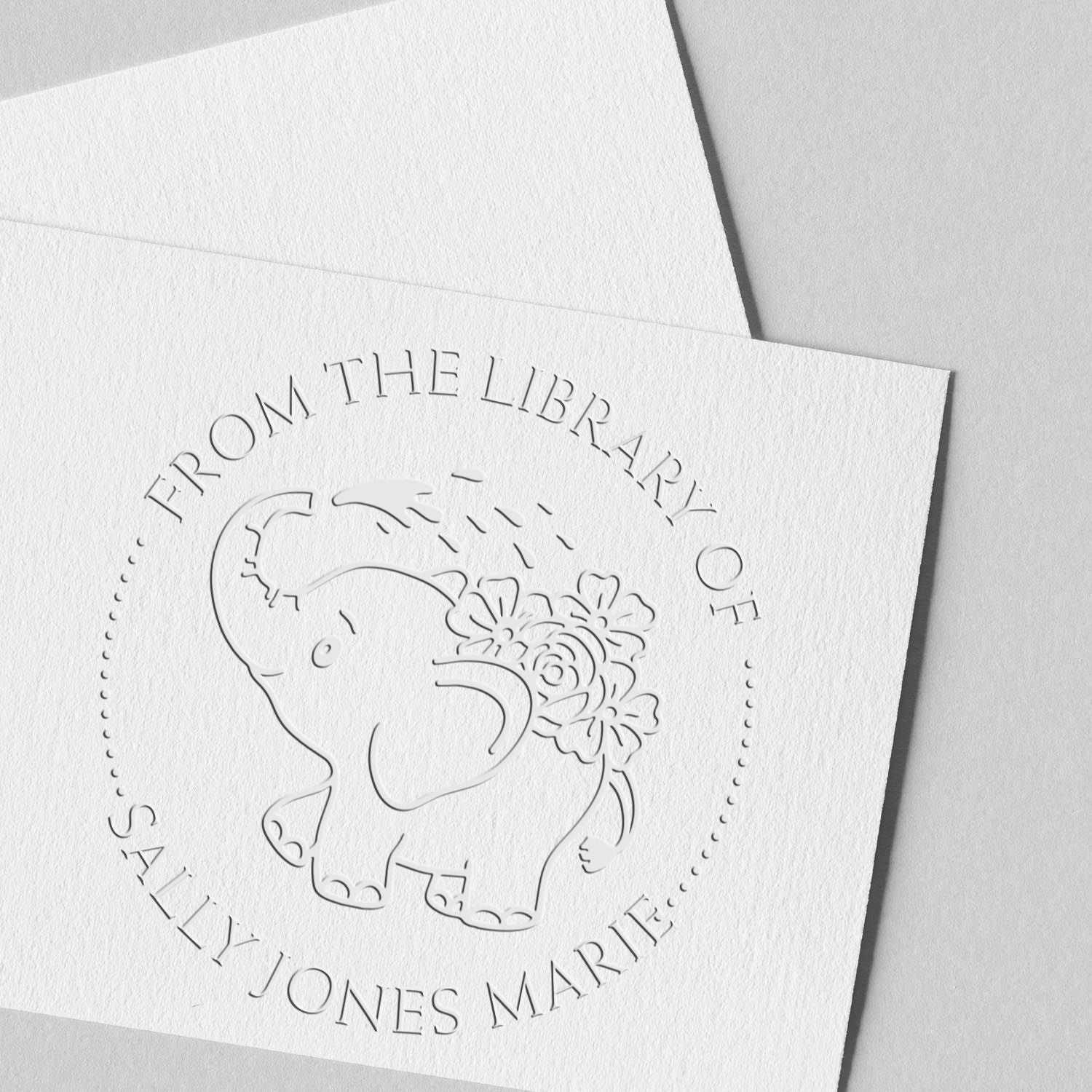 White embossed paper stamp seal featuring an elephant with flowers and circular text, From the Library of Sally Jones Marie.