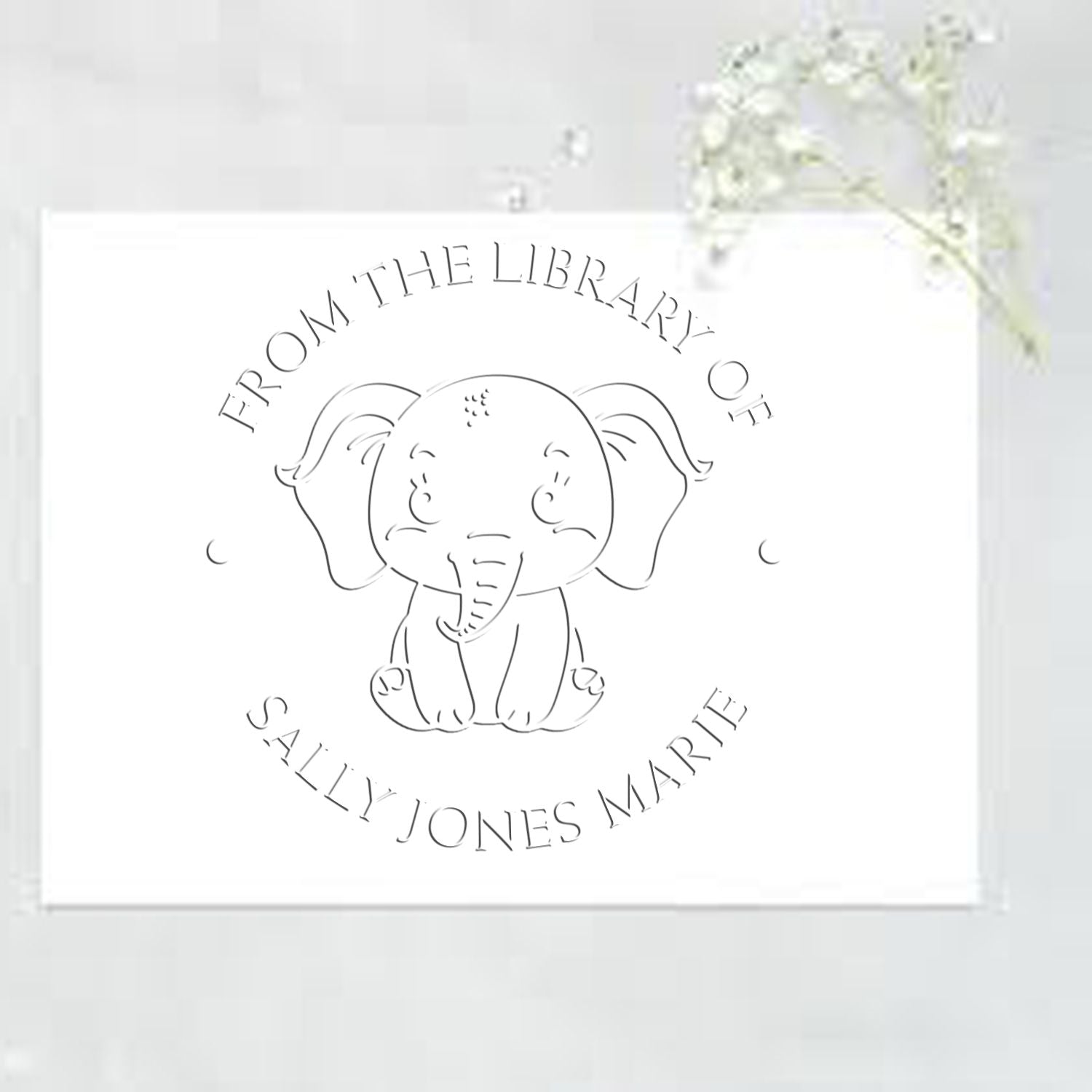 White custom library stamp seal with a line-art elephant and circular text on a pale card.