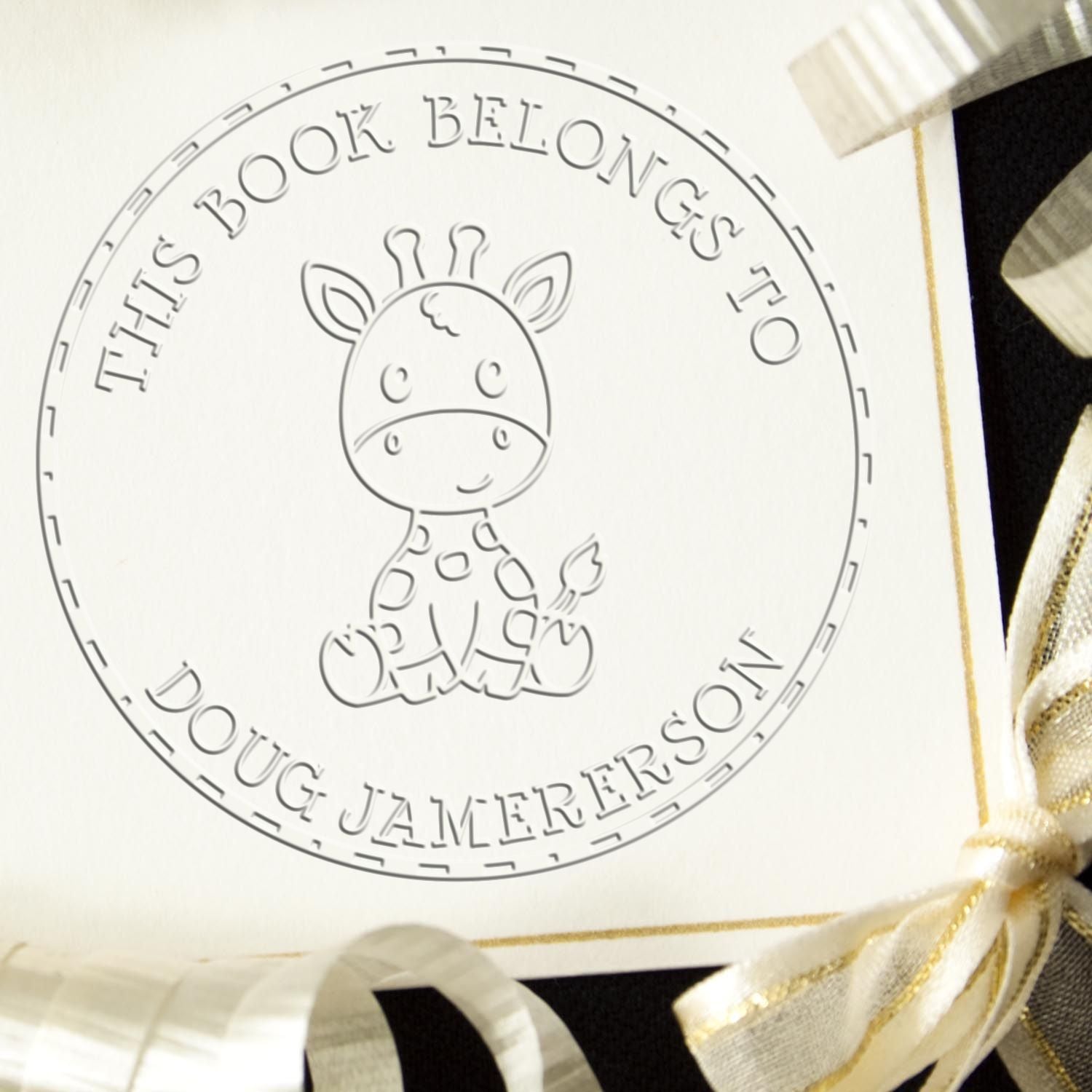 Personalized round book stamp seal with giraffe outline, black lettering, and white-gold ribbon accents.