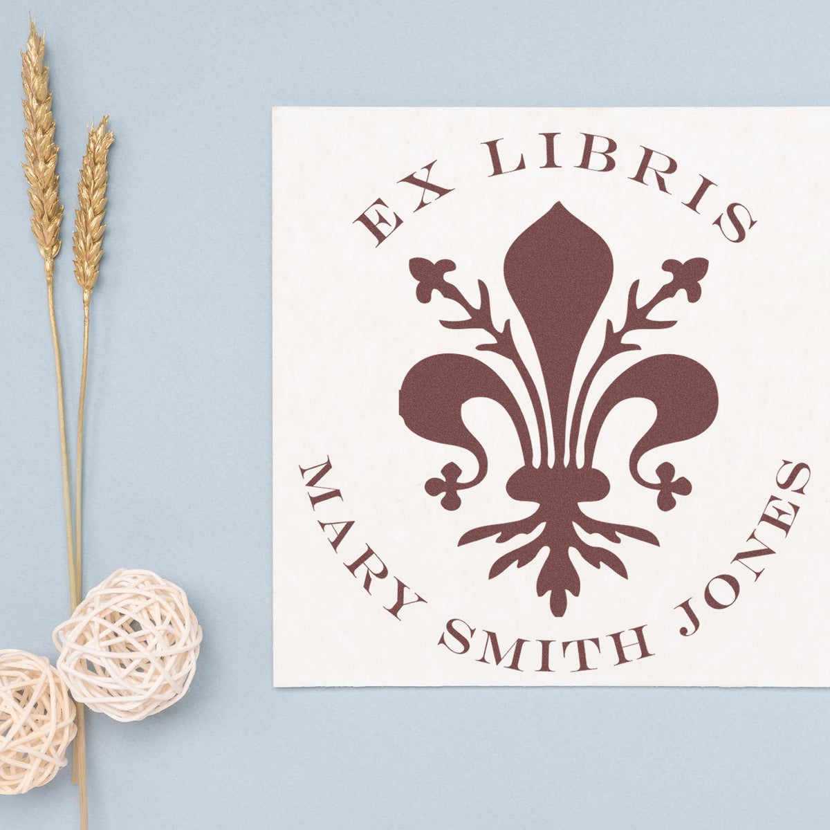 Burgundy Ex Libris Mary Smith Jones stamp and seal with fleur-de-lis emblem on white card, pale blue background.