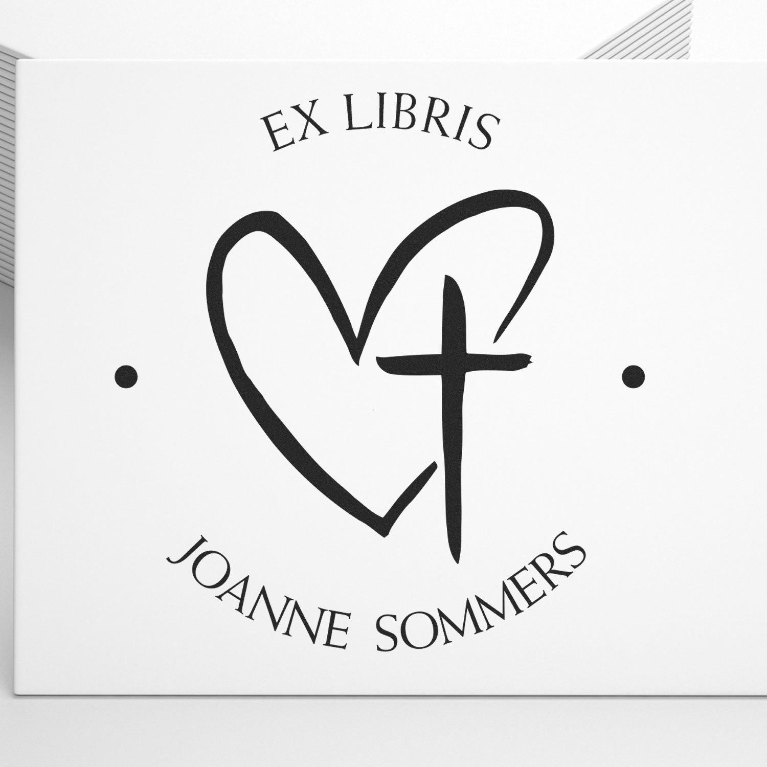 Black Ex Libris stamp seal with heart and cross design, Joanne Sommers text on white background.