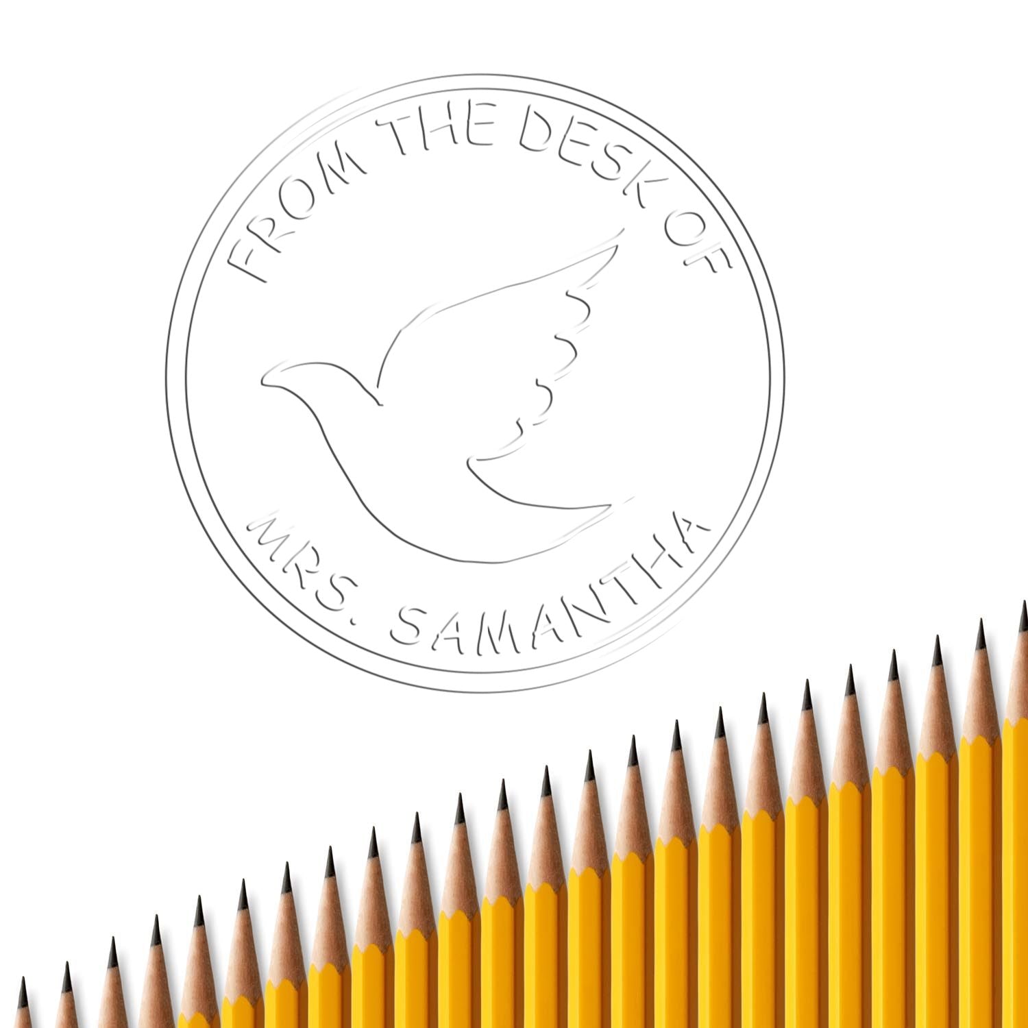 Circular personalized desk stamp seal with dove outline and From the desk of Mrs. Samantha, over yellow pencils.