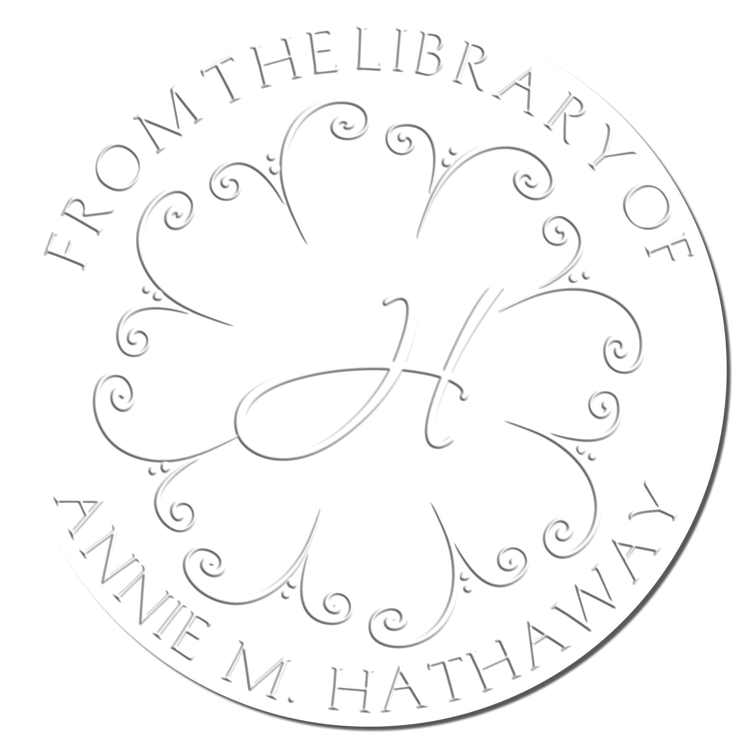 Silver circular library seal stamp with ornate floral monogram and text "From the Library of Annie M. Hathaway" on white.