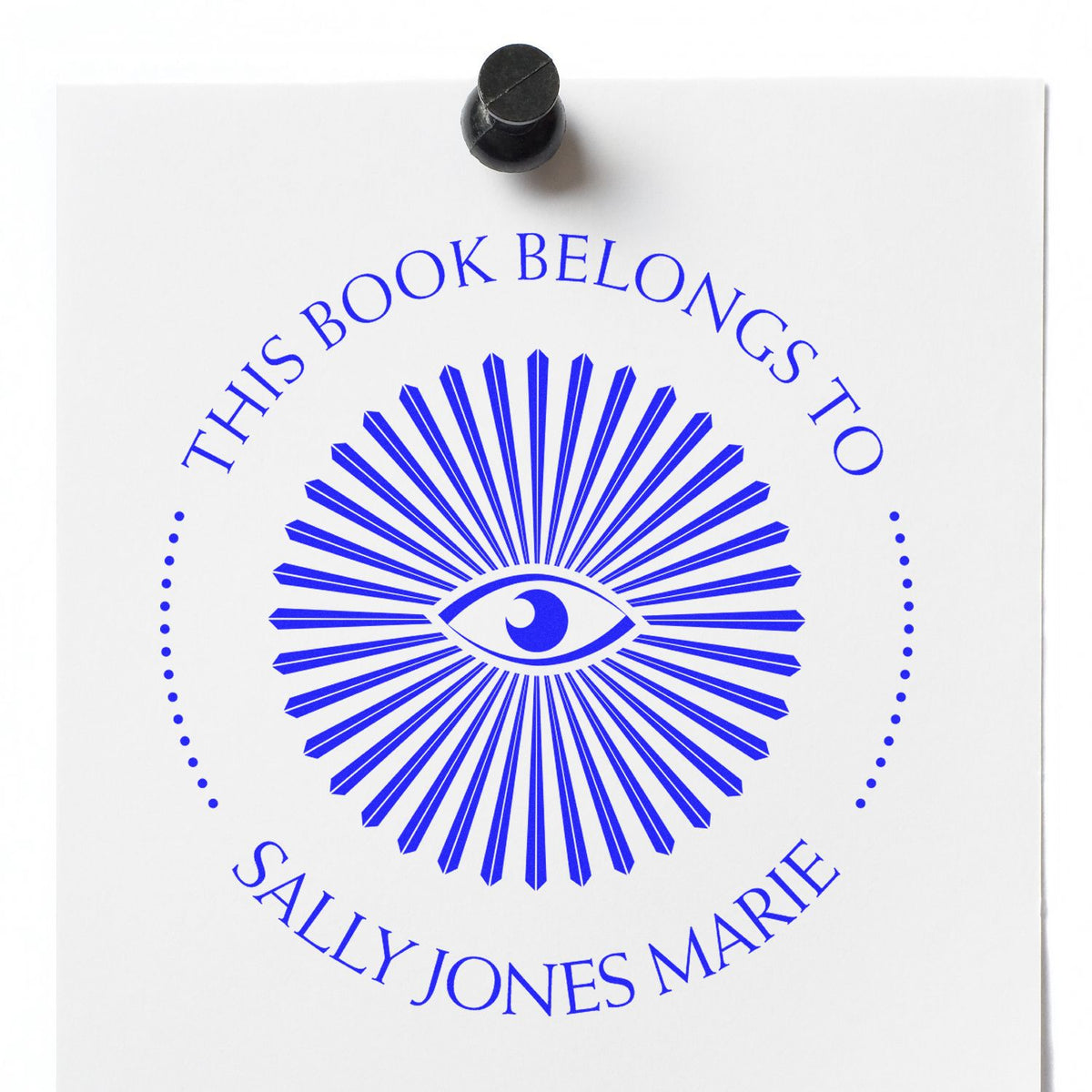 Blue book ownership stamp seal with eye emblem and black handle on white paper, reading This book belongs to Sally Jones Marie