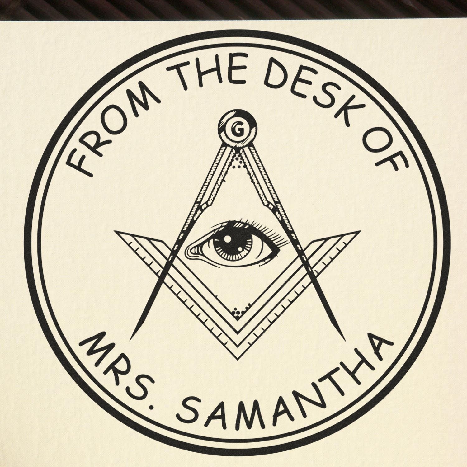 Black circular desk seal stamp with compass-and-eye emblem, cream background, reading From the Desk of Mrs. Samantha.