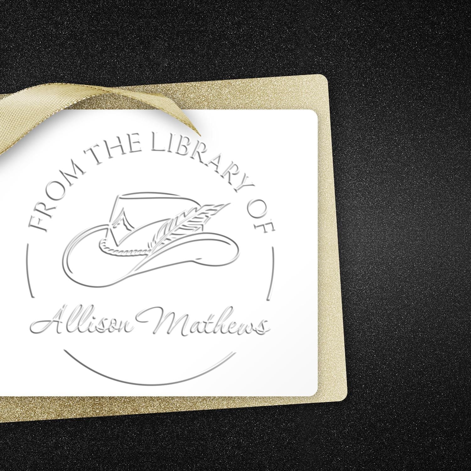 Custom silver-embossed library stamp seal on white card, with gold ribbon and glittery gold border on black background.