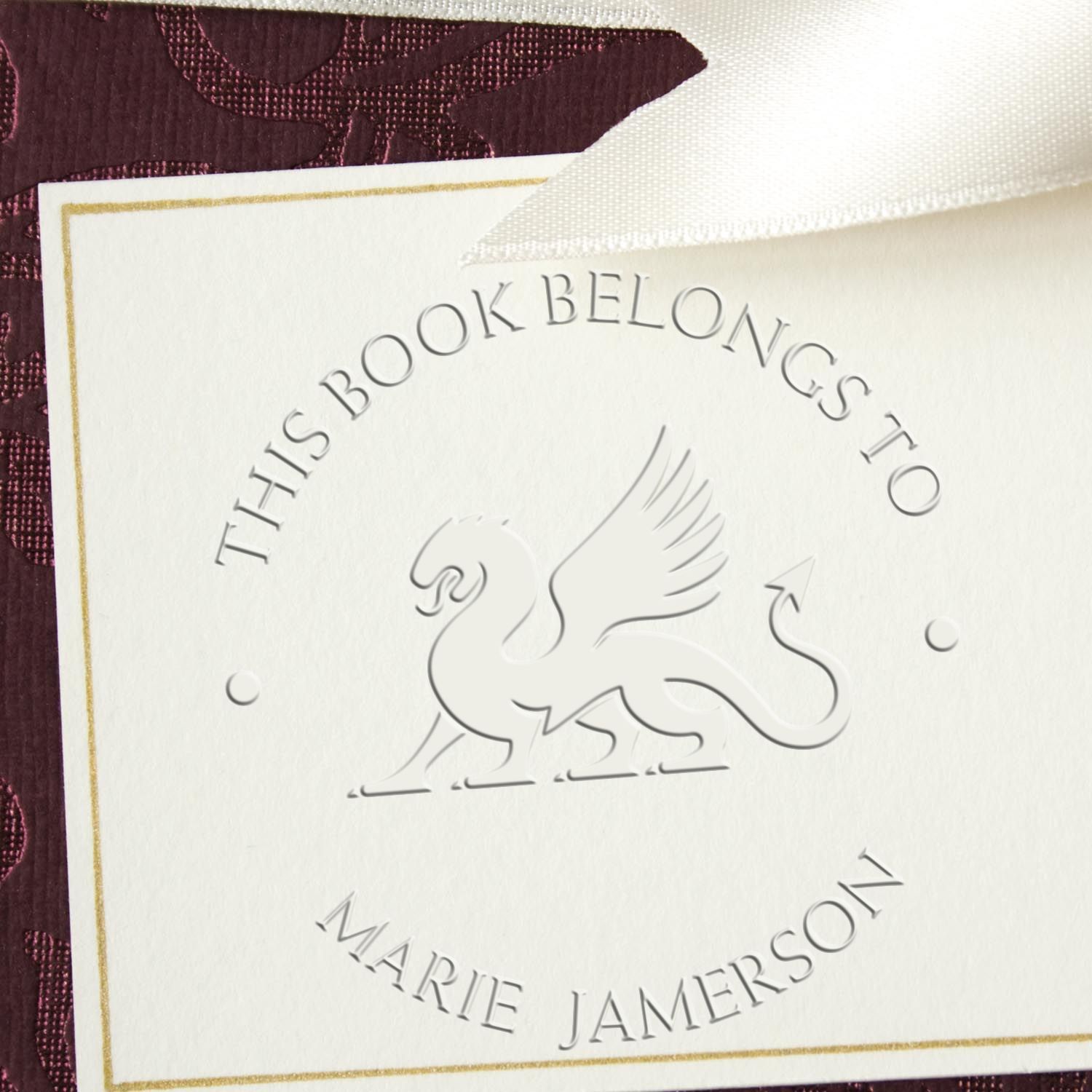 White embossed bookplate seal with silver swan, gold border, and This Book Belongs to Marie Jamerson on purple background.