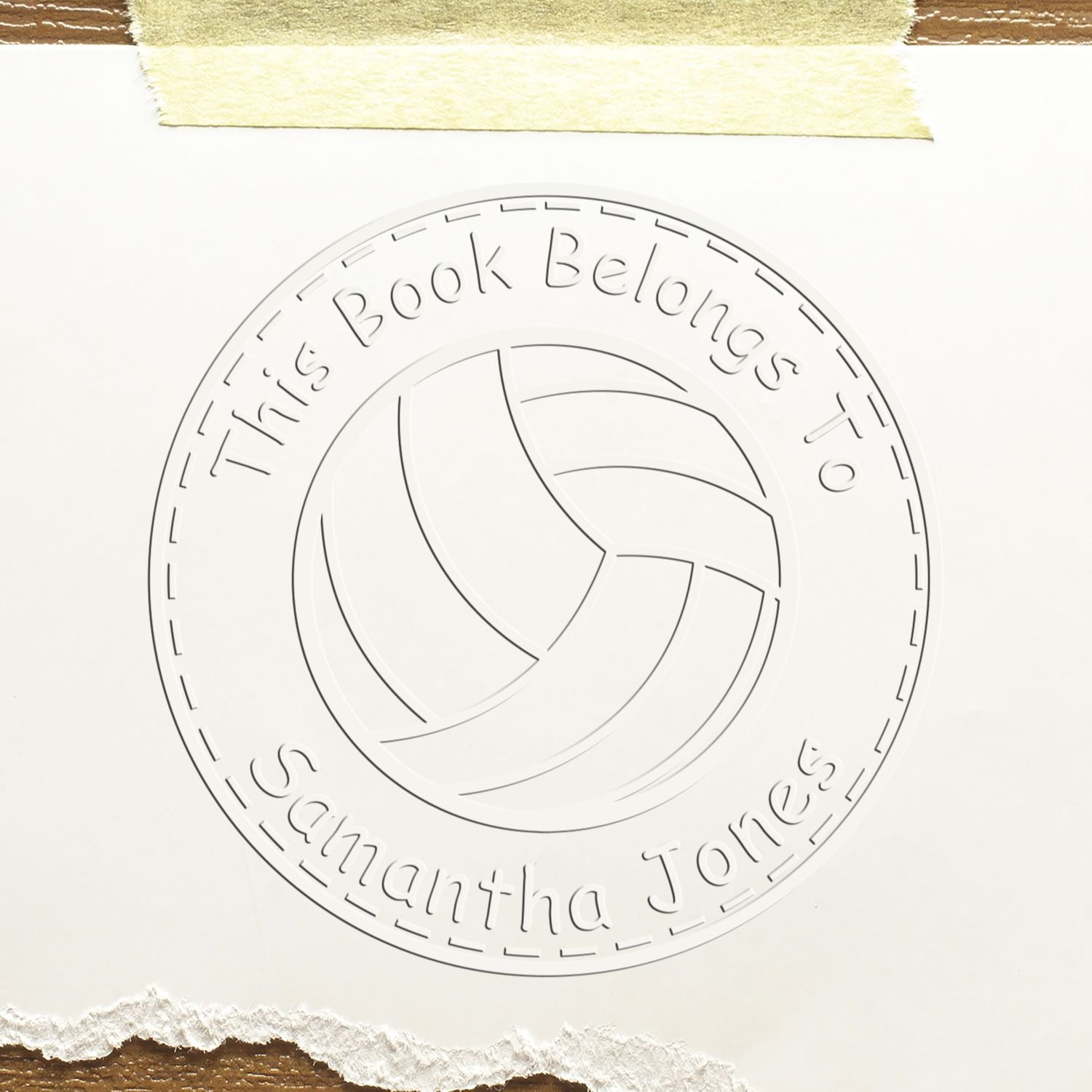 Embossed white book ownership stamp seal with circular border and text This Book Belongs to Samantha Jones.