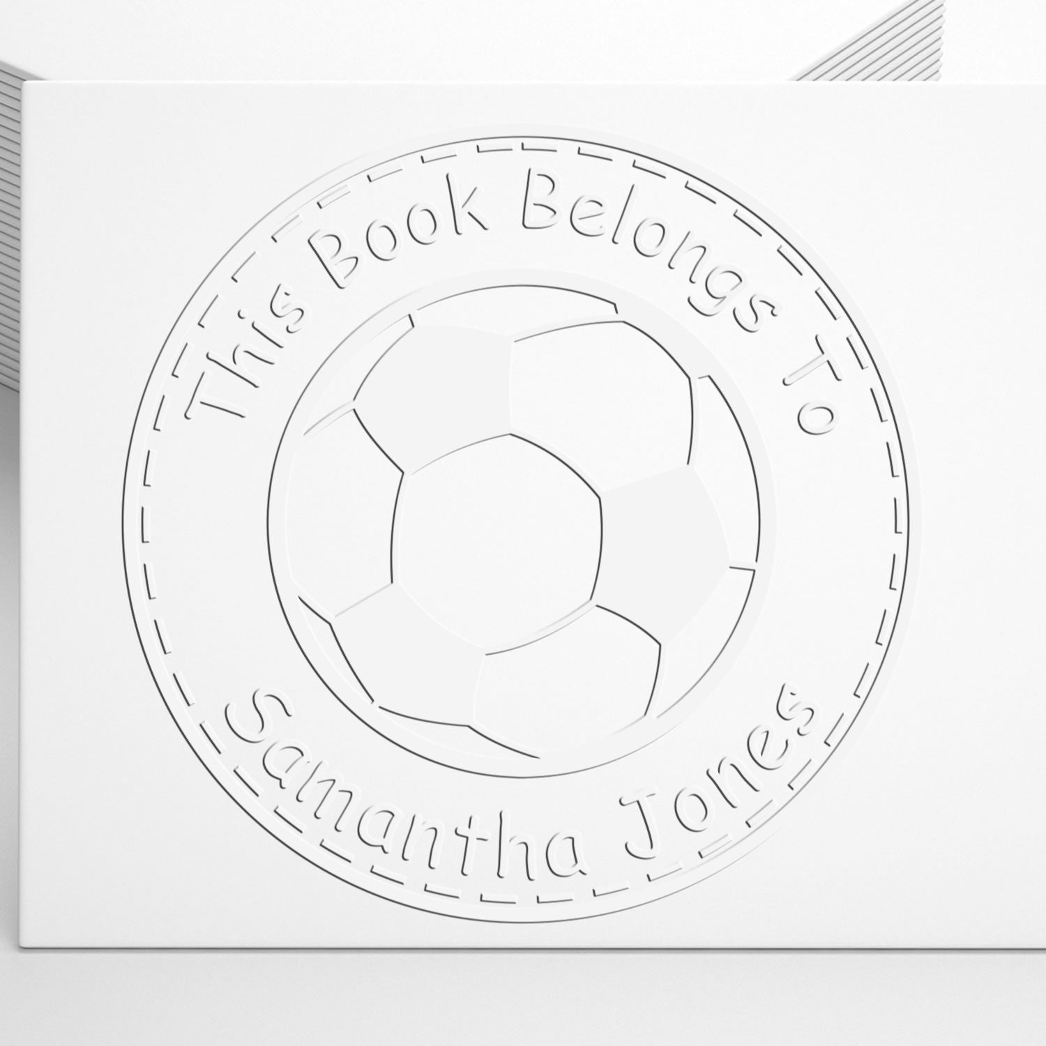 White embossed book ownership stamp with circular soccer ball seal and This Book Belongs To Samantha Jones text.