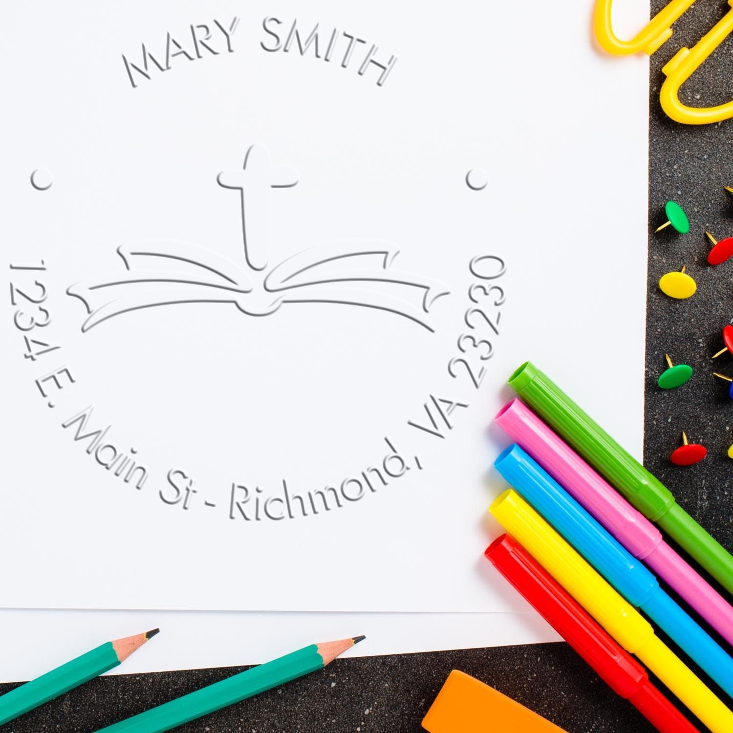 Embossed notary stamp seal for Mary Smith, with gray cross emblem on white paper, surrounded by colorful pens and pencils.
