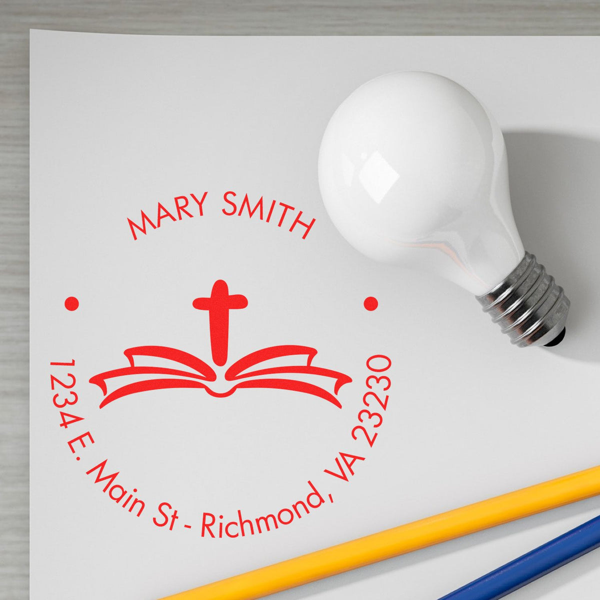 Red custom stamp and seal for Mary Smith with cross, address, and white light bulb on white paper.