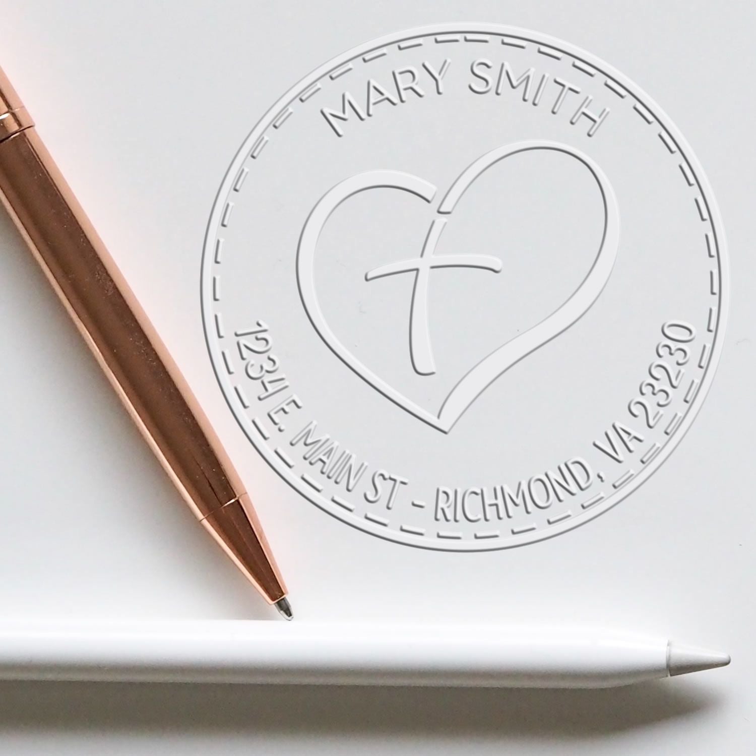 White embossed custom seal stamp with heart-and-cross logo, rose-gold pen, and white stylus.