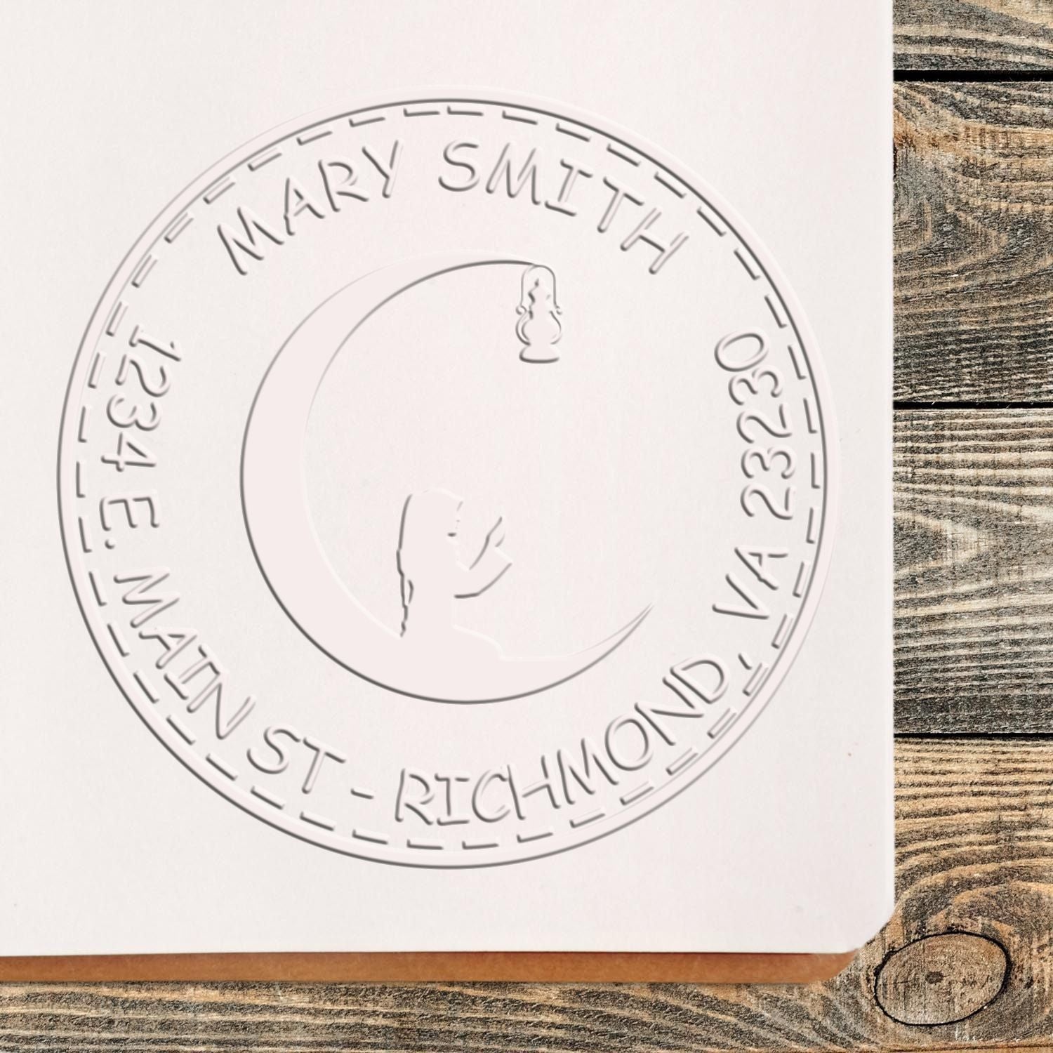 White embossed custom round stamp seal for Mary Smith with name, address, and monogram on light wood.
