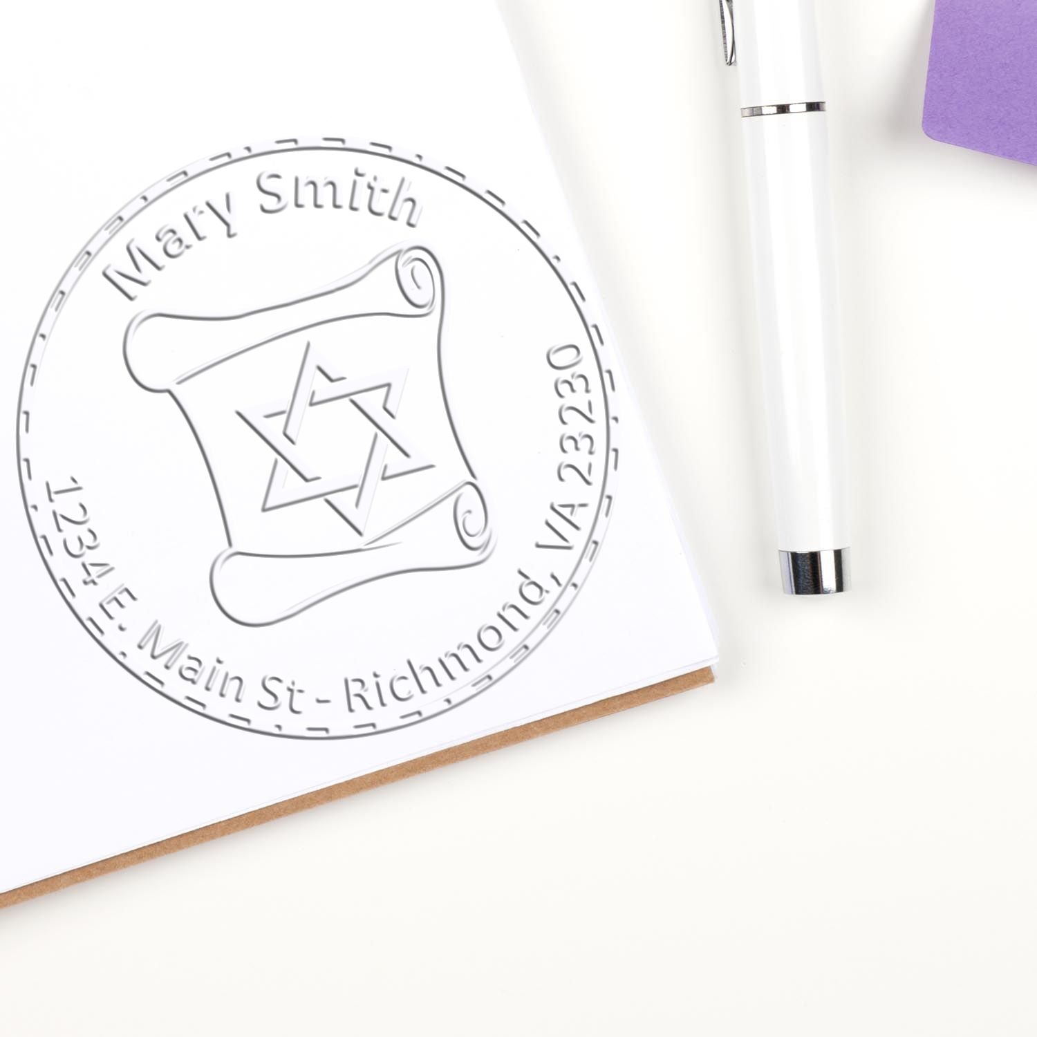 Custom embossed seal stamp on white paper, with circular Mary Smith return-address design and white pen on a purple-accented background.