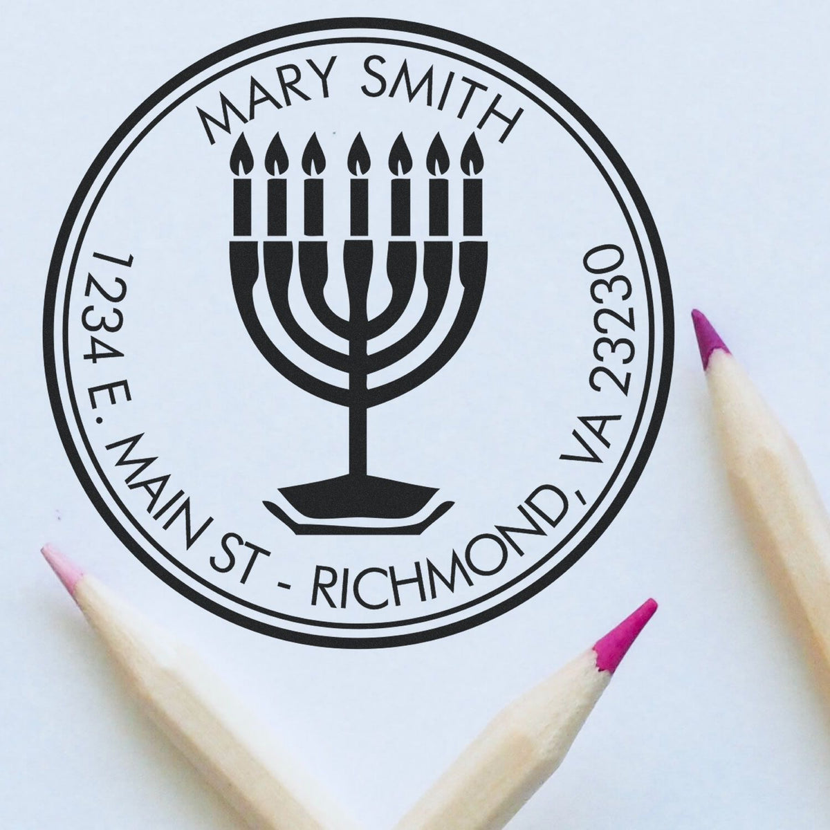 Black custom rubber stamp seal with menorah, Mary Smith, and Richmond, VA address on white background, framed by pink pencil tips.