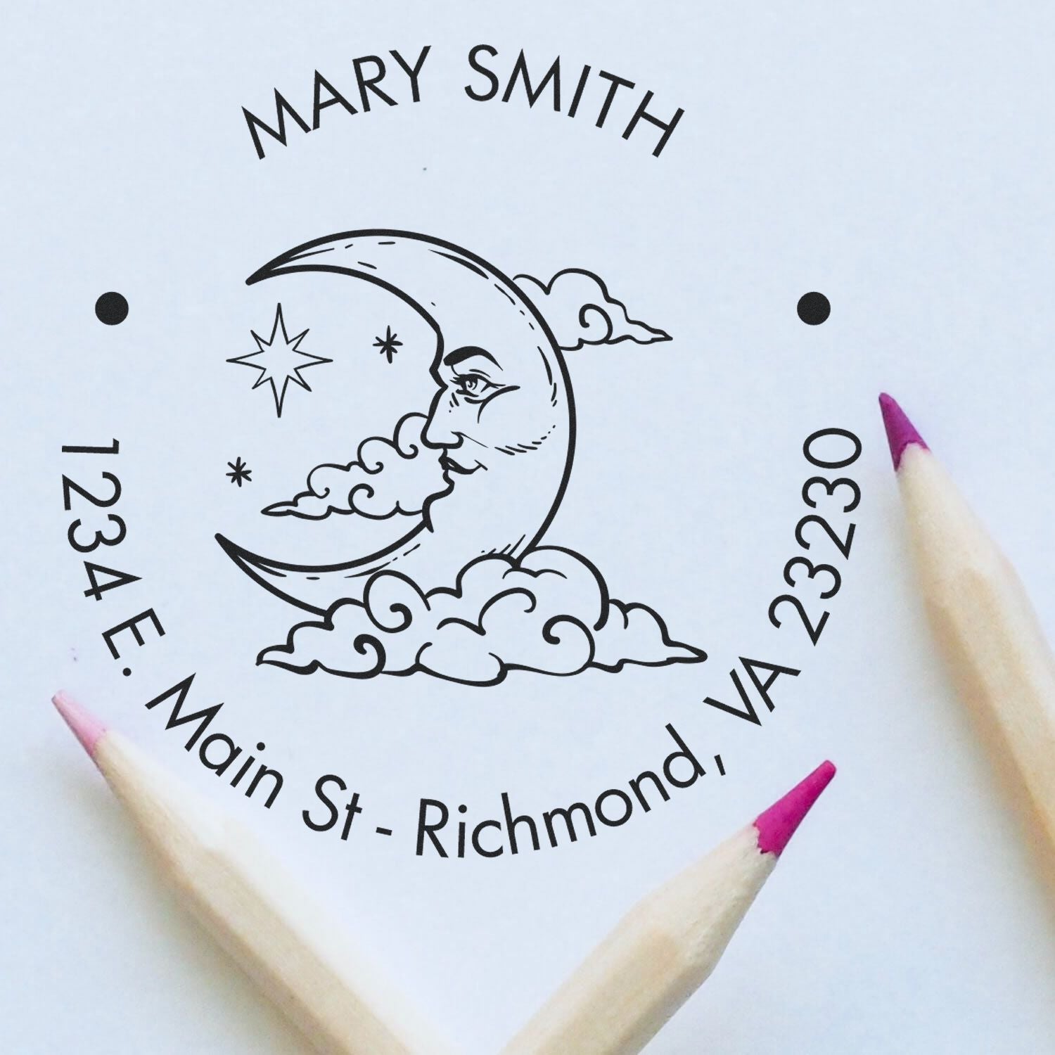 Black custom seal stamp for Mary Smith with crescent moon, clouds and stars on white paper, framed by pink-tipped pencils.