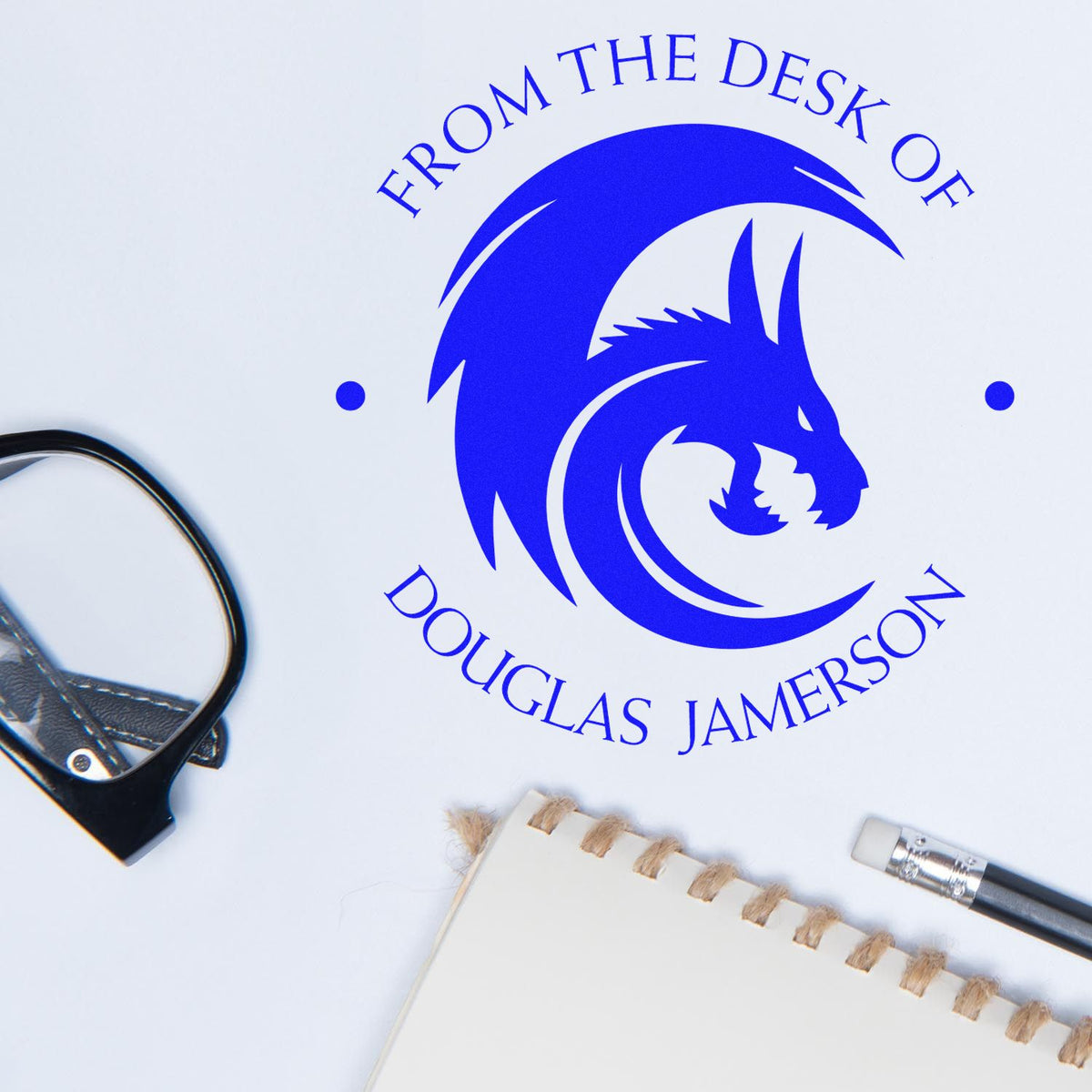 Blue custom stamp seal with dragon logo and From the Desk of Douglas Jamerson on white paper, beside a binder clip and pencil.