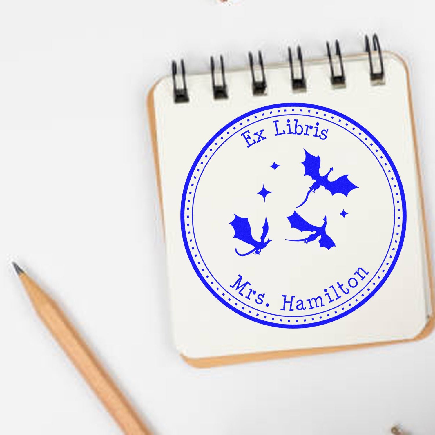 Blue Ex Libris custom stamp seal with bats and Mrs. Hamilton in bold blue on a spiral notebook.