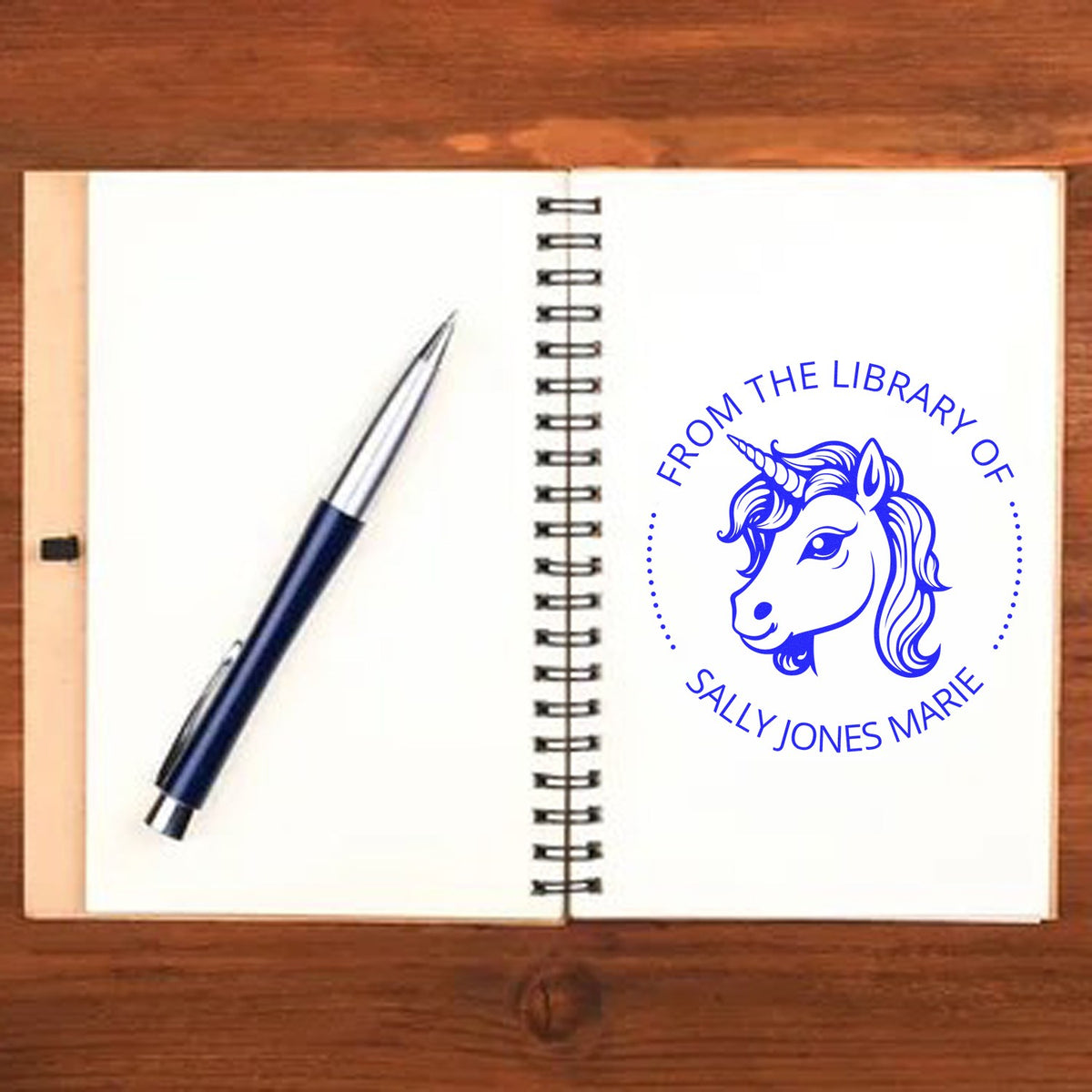 Spiral notebook with navy pen and blue unicorn library ownership stamp seal in blue, personalized with Sally Jones Marie.