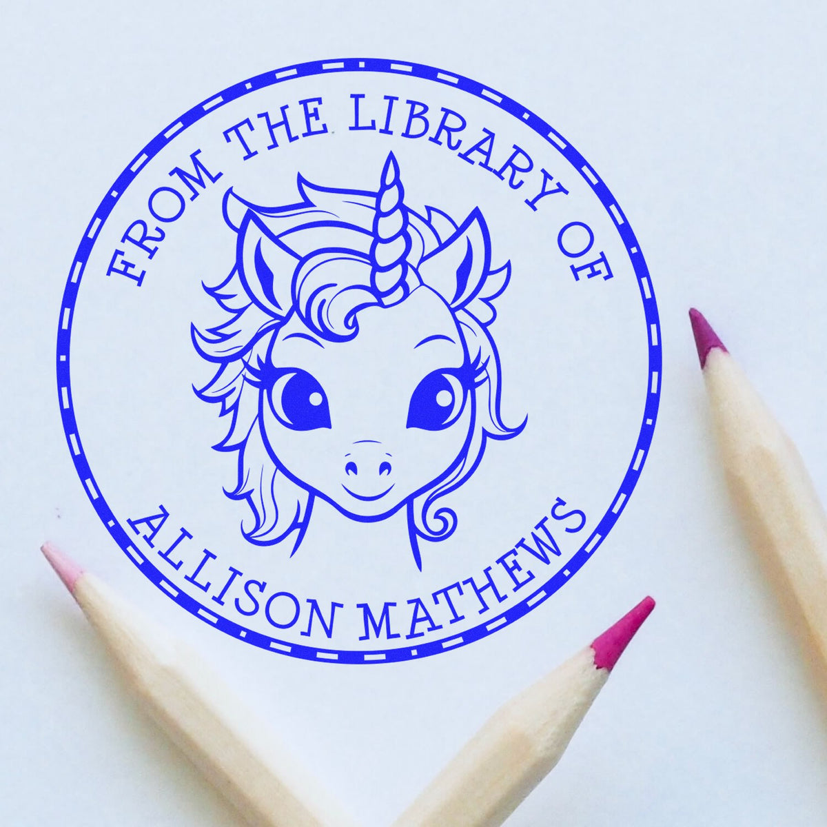 Blue circular unicorn library stamp seal with From the Library of Allison Matthews and pink-tipped pencils around it.