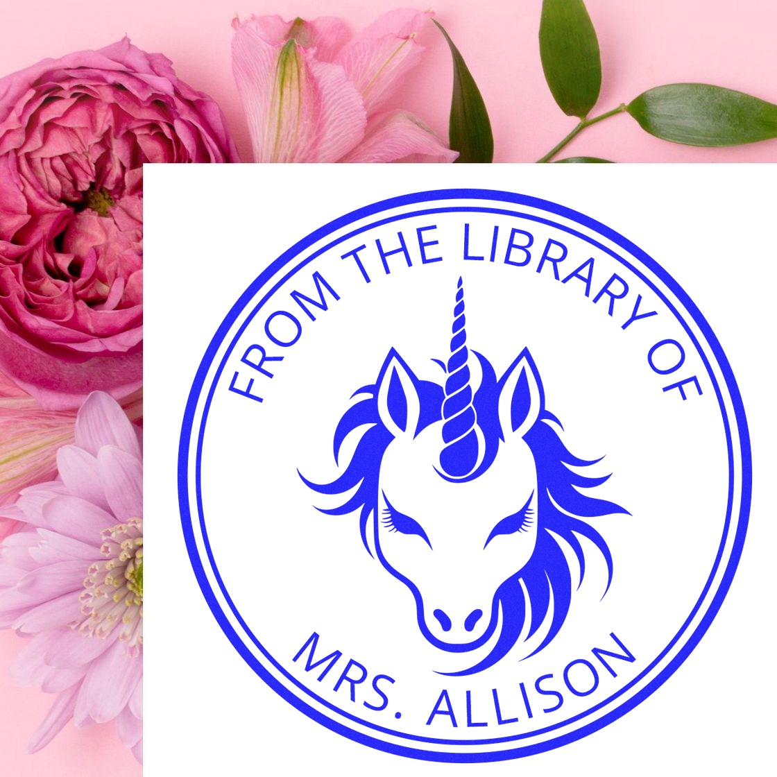 Blue circular unicorn library stamp seal for Mrs. Allison on white, set against a pink floral background.