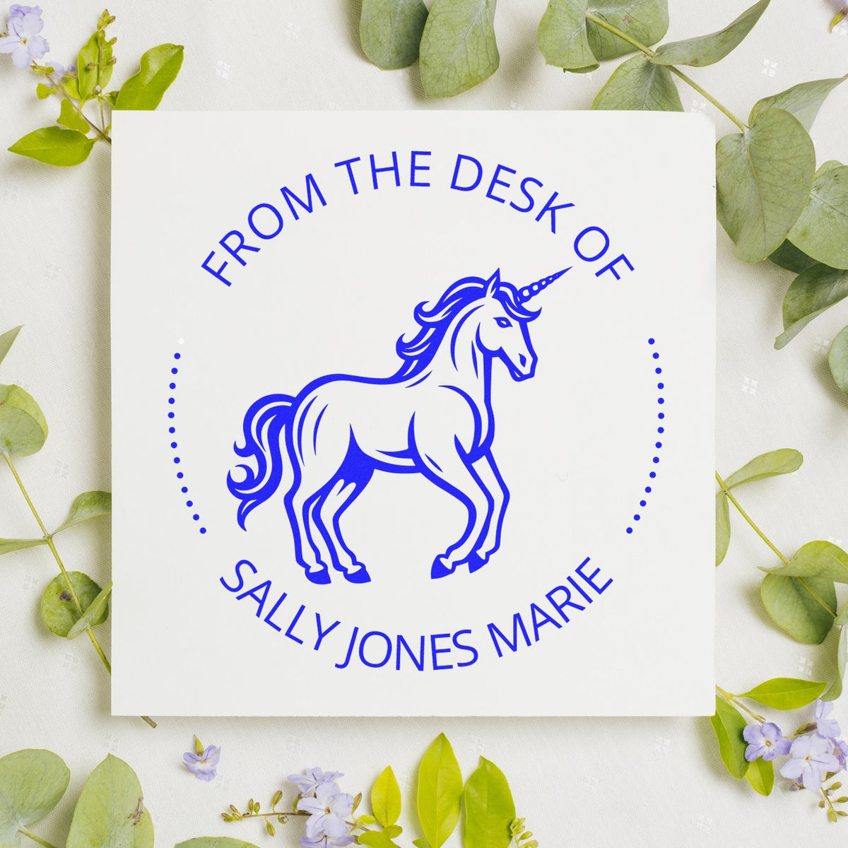 Blue unicorn stamp seal design with ĀFrom the Desk of Sally Jones MarieĀ in cobalt blue on a white square, framed by green leaves.