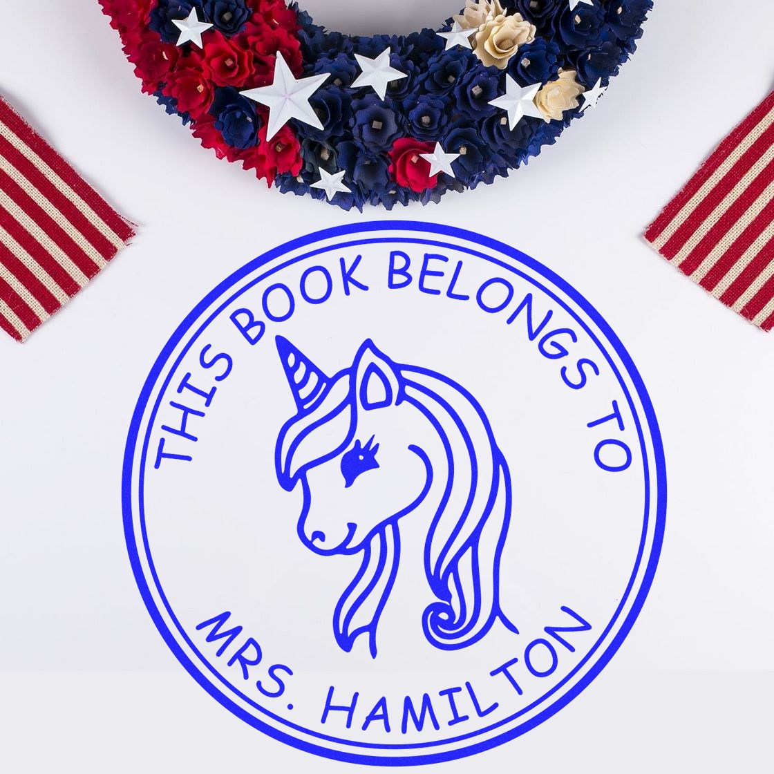 Blue round unicorn book seal stamp reading This Book Belongs to Mrs. Hamilton, with red, white, and blue patriotic accents.