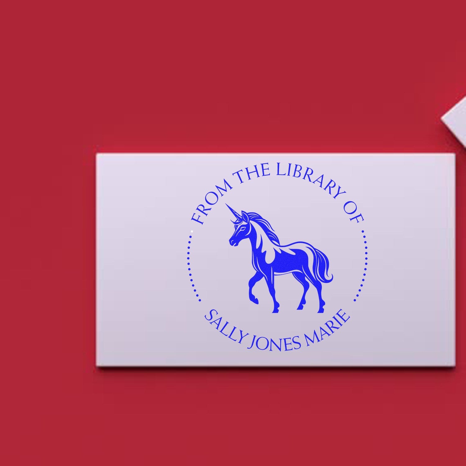 Blue unicorn library seal stamp on white card against red background, reading From the Library of Sally Jones Marie.