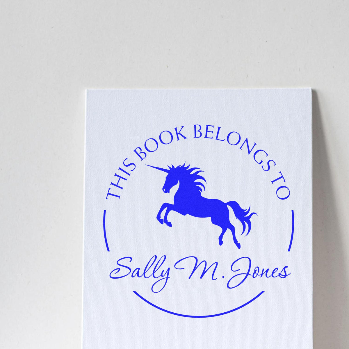 Blue unicorn stamp seal on white card with This Book Belongs To and Sally M. Jones.