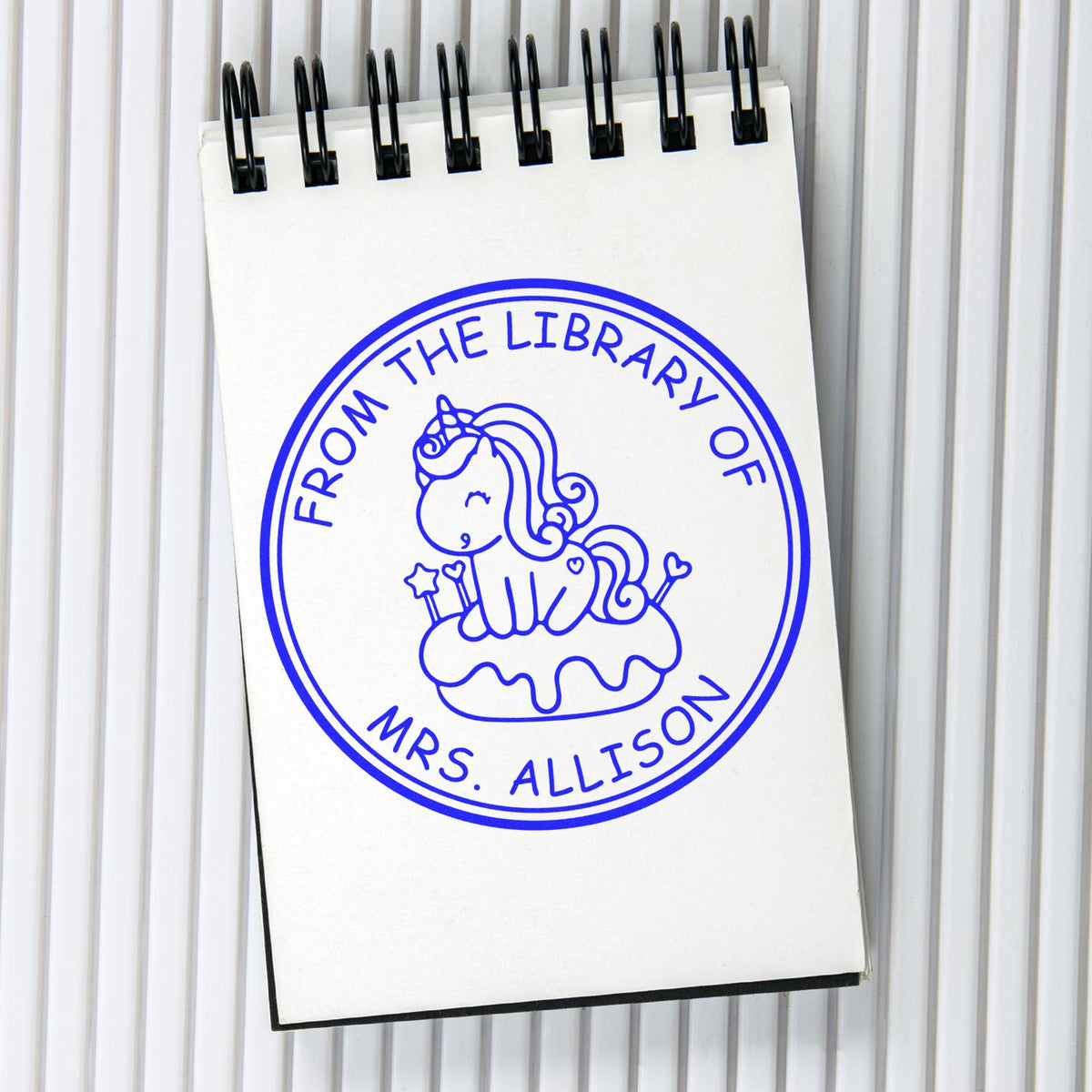 Blue custom stamp seal on a white notepad, with a unicorn and circular text: From the Library of Mrs. Allison.