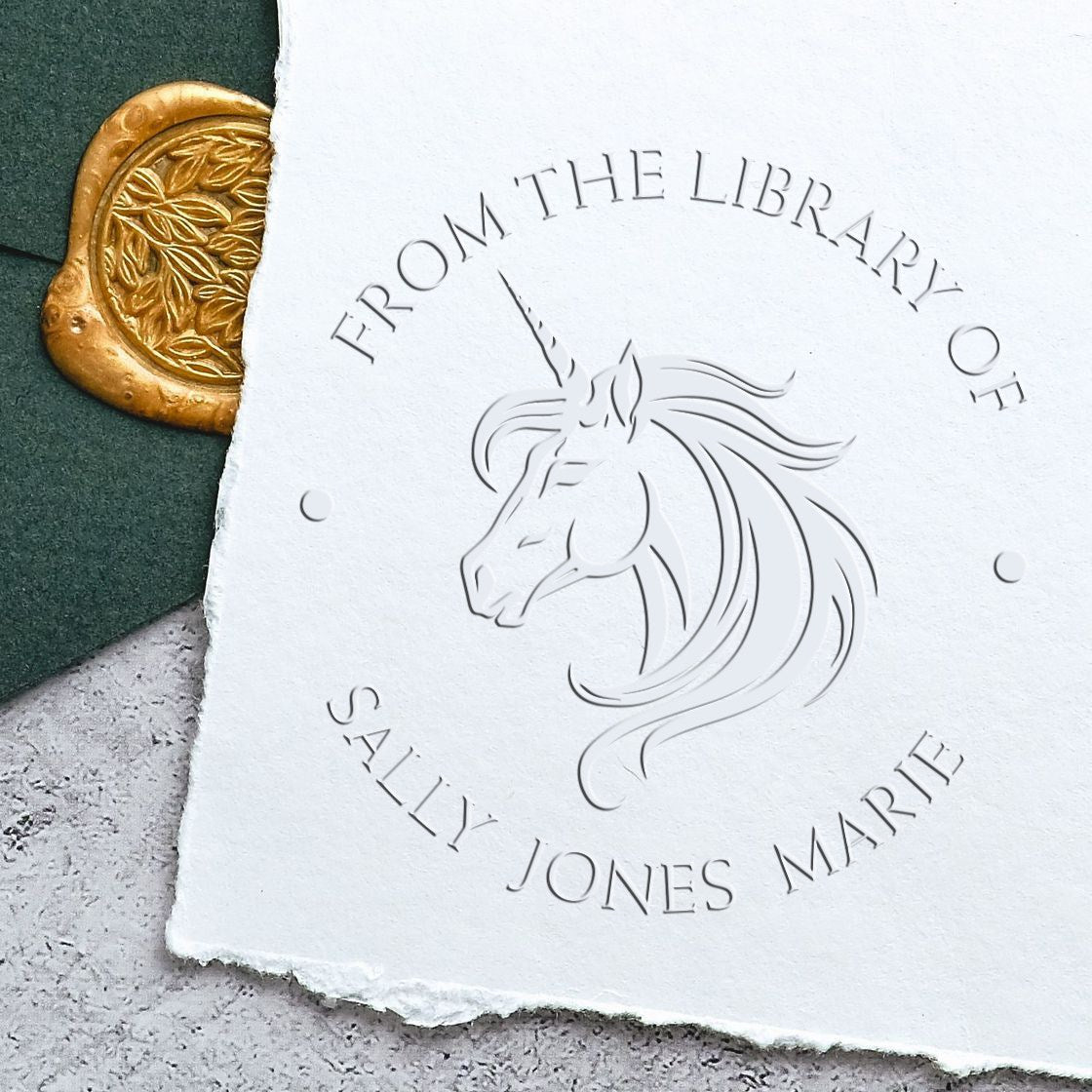White embossed unicorn stamp seal reading From the Library of Sally Jones Marie, beside a gold wax seal on dark green paper.