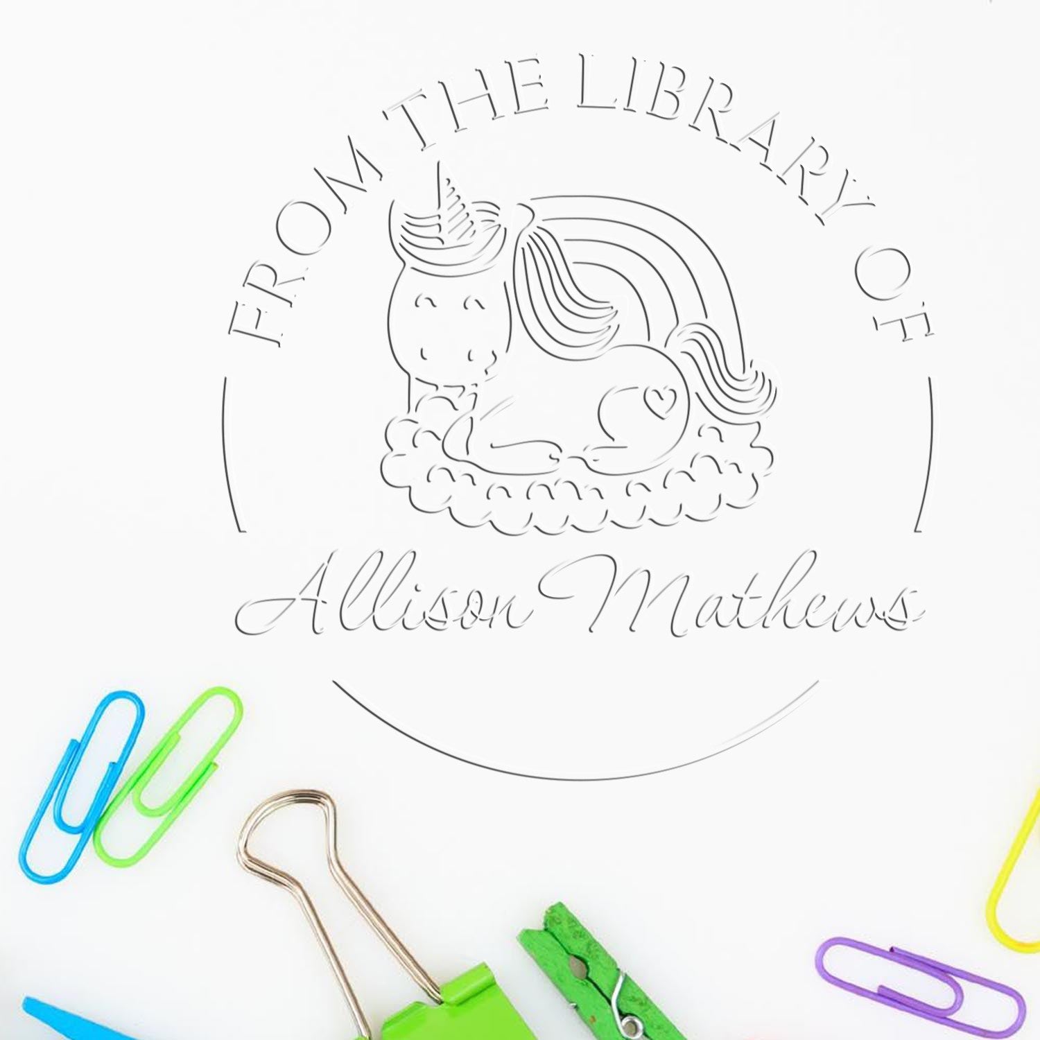 Custom library stamp seal with unicorn outline and “From the Library of Allison Matthews” in gray, surrounded by colorful paper clips.