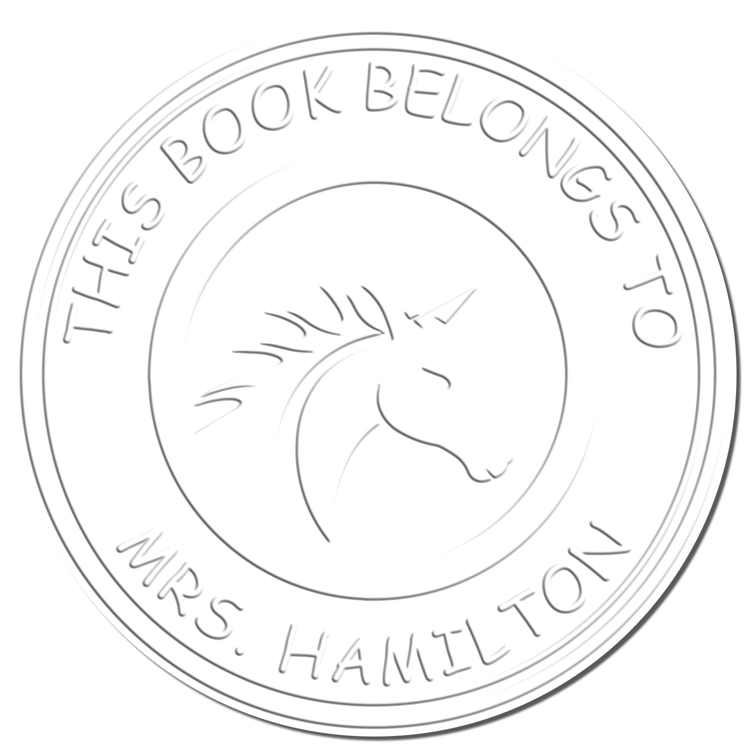 Silver circular book stamp seal with unicorn head and embossed This Book Belongs to Mrs. Hamilton text on white background.