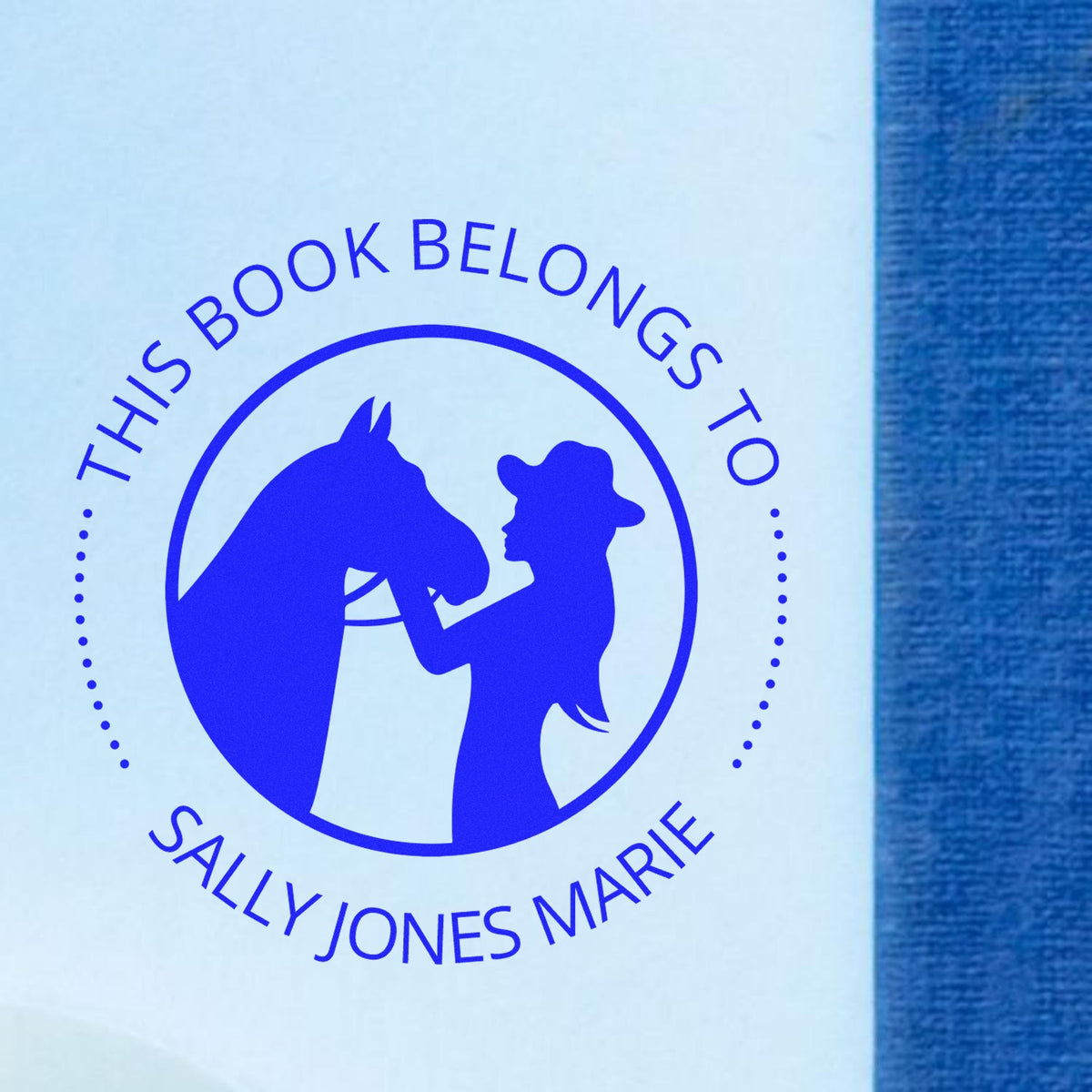 Blue custom book ownership stamp seal with horse and woman silhouette, reading ĀThis book belongs to Sally Jones MarieĀ