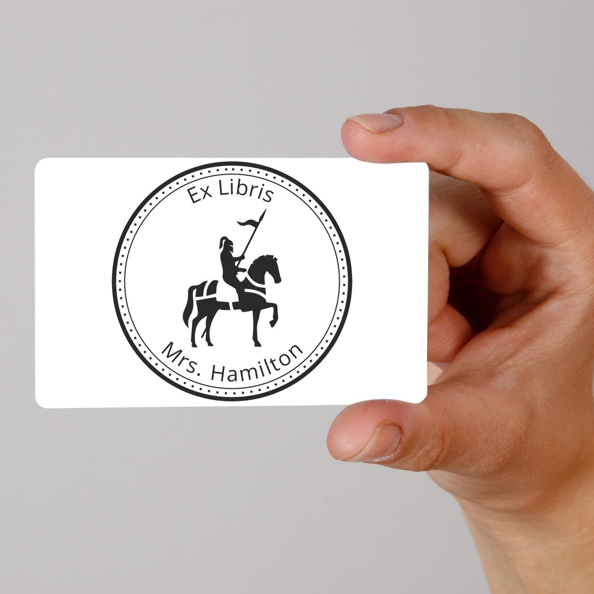 Hand holding white stamp and seal card with black Ex Libris Mrs. Hamilton knight seal design