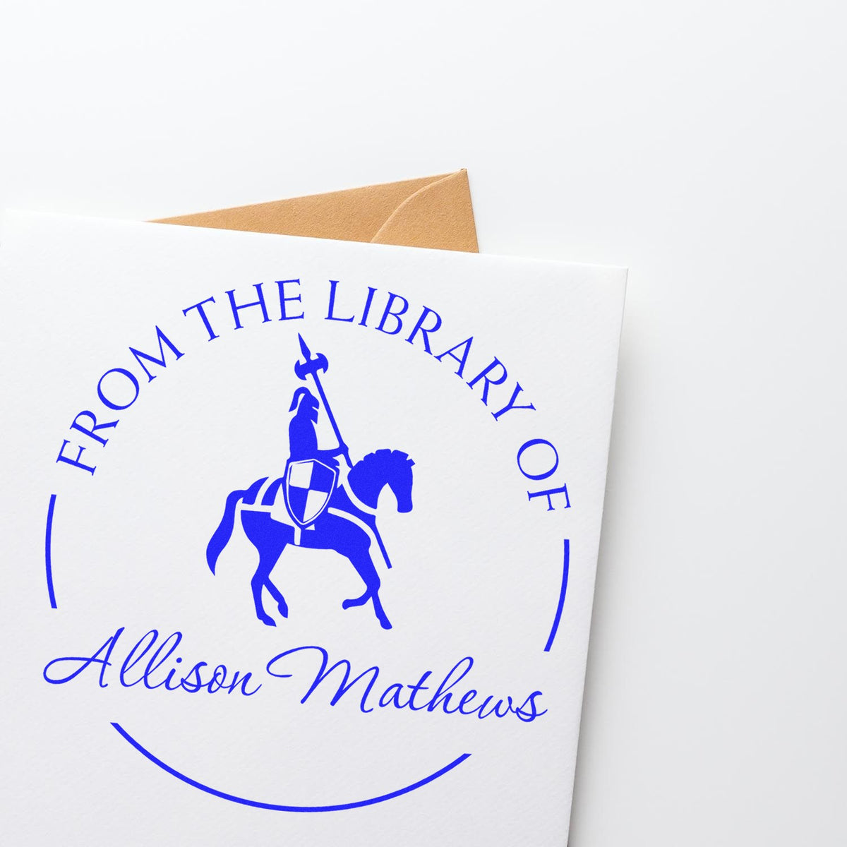 Blue custom library stamp seal on white card with knight on horseback and Allison Mathews, backed by a brown envelope.