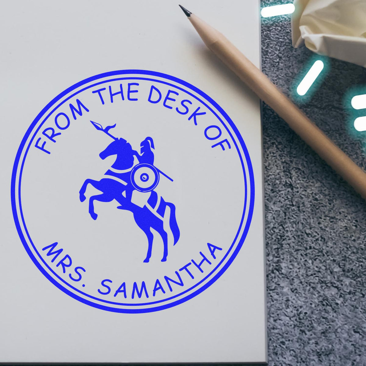 Blue custom desk stamp seal with rearing horse logo and From the Desk of Mrs. Samantha on white paper.
