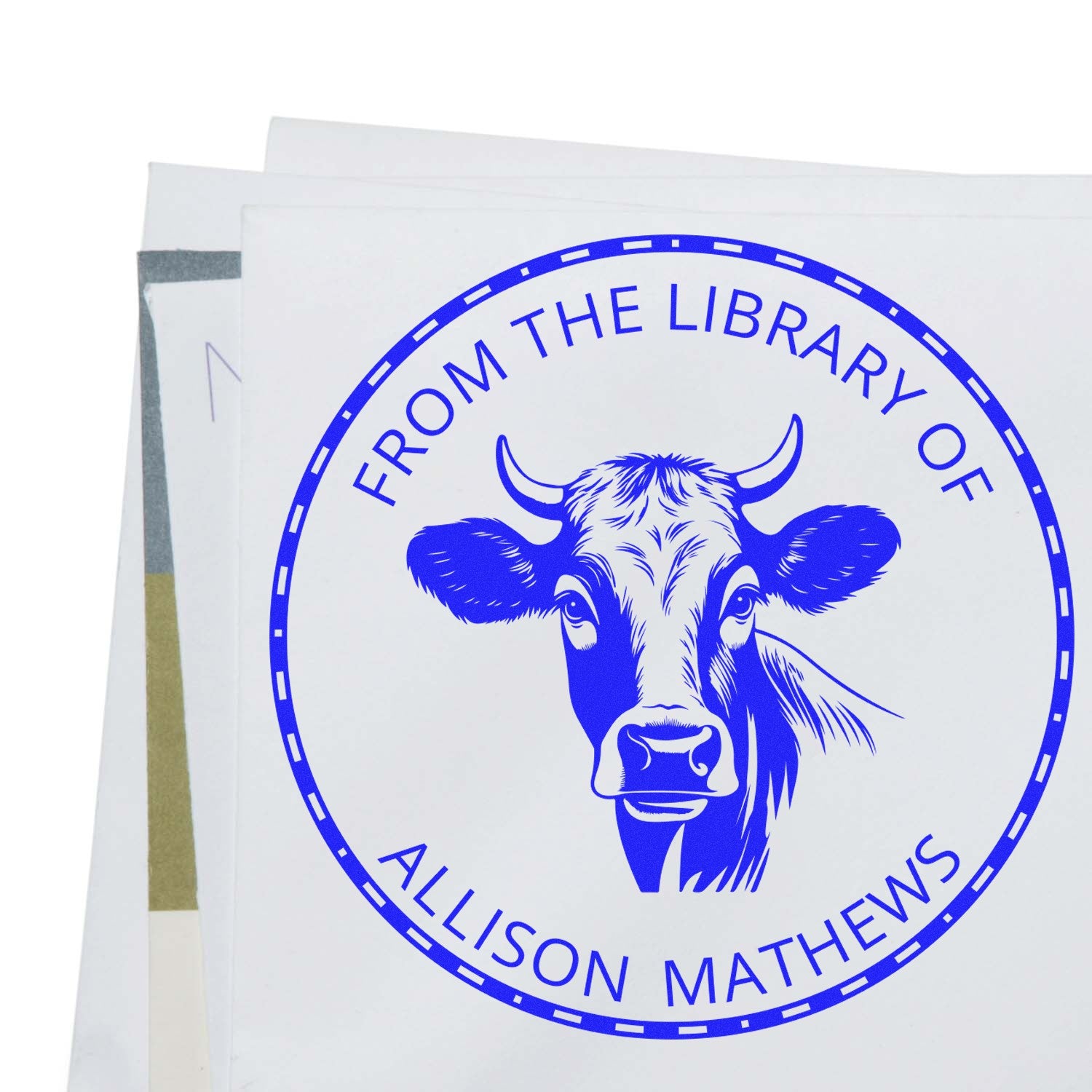 Blue custom stamp seal with cow head and circular text reading From the Library of Allison Mathews