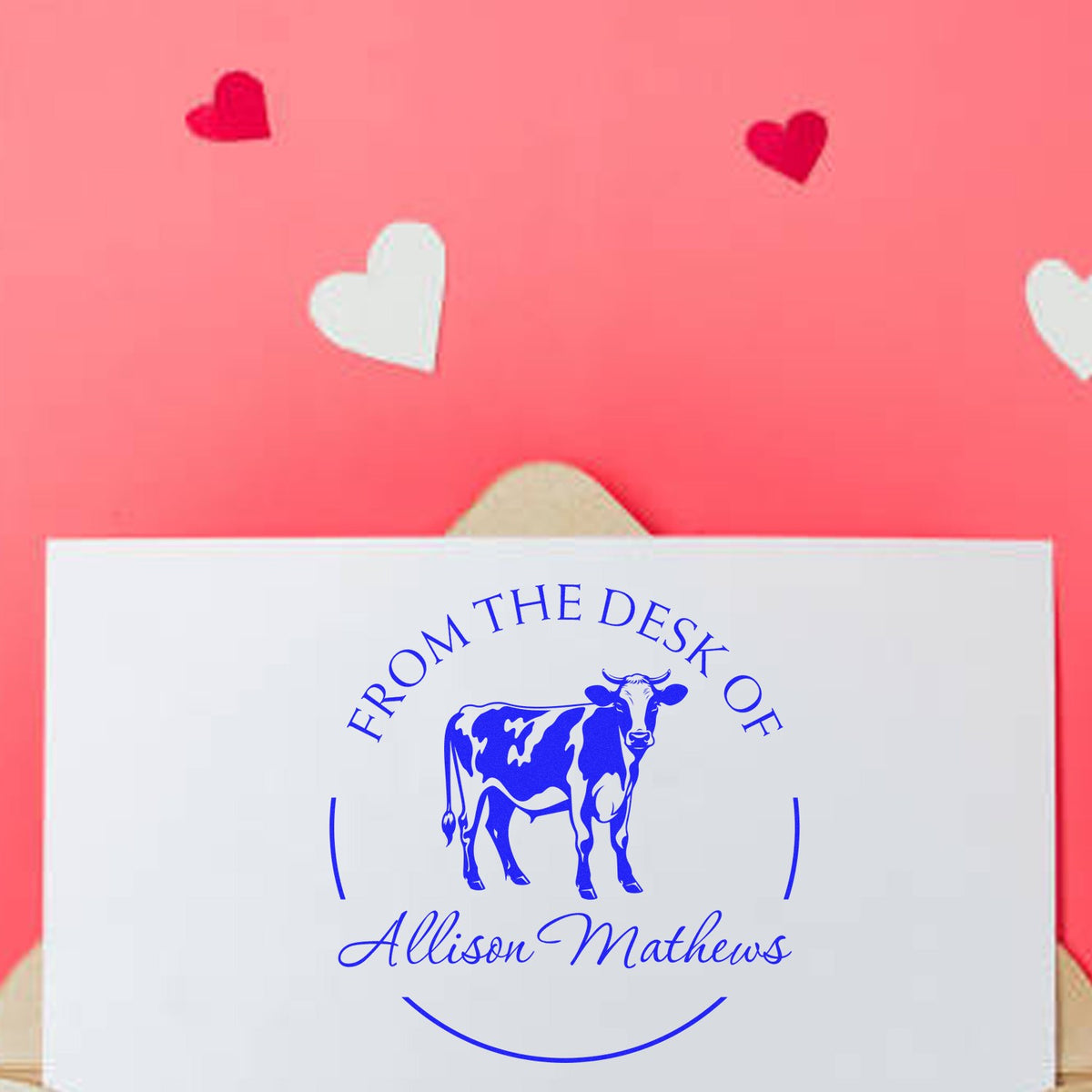 Blue custom cow From the Desk of Allison Mathews stamp seal on white card, with pink heart background.