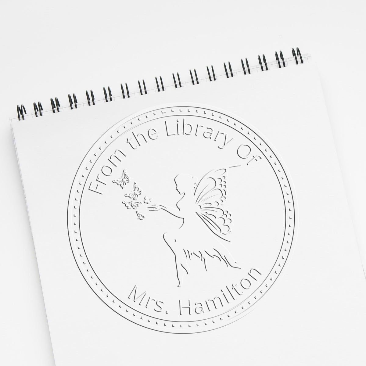 ESS Seraphina Mythical Fairy handheld personalized book embosser with fantasy stamp design in use on paper.