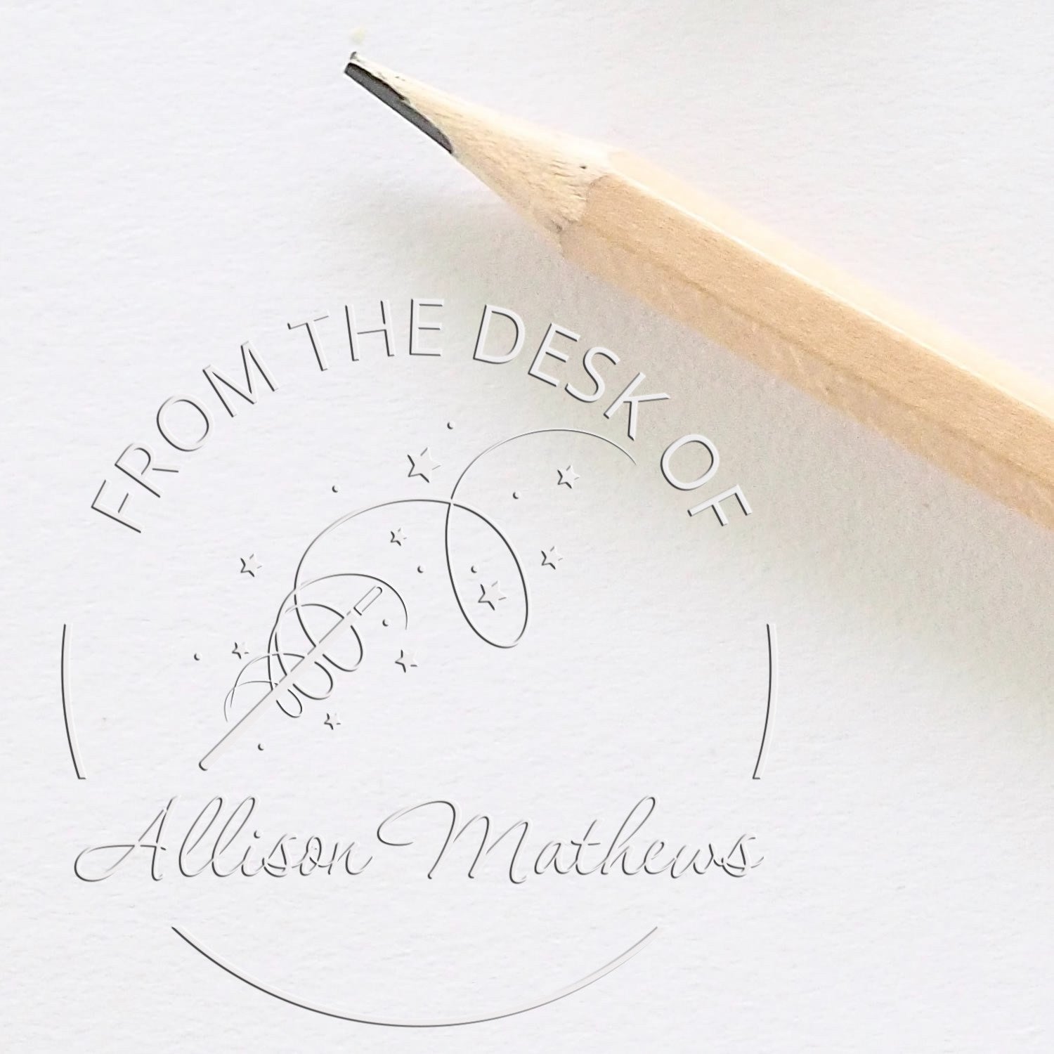 White custom stamp and seal with pencil tip, reading From the Desk of Allison Matthews and a starry rocket design.