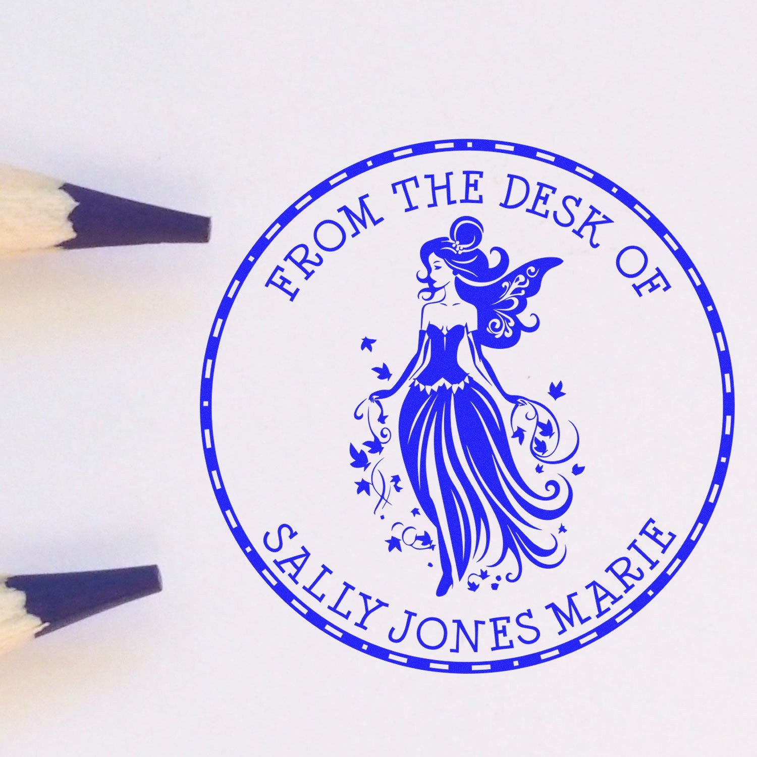 Blue custom stamp seal with fairy motif and From the Desk of Sally Jones Marie, shown beside pencil tips.