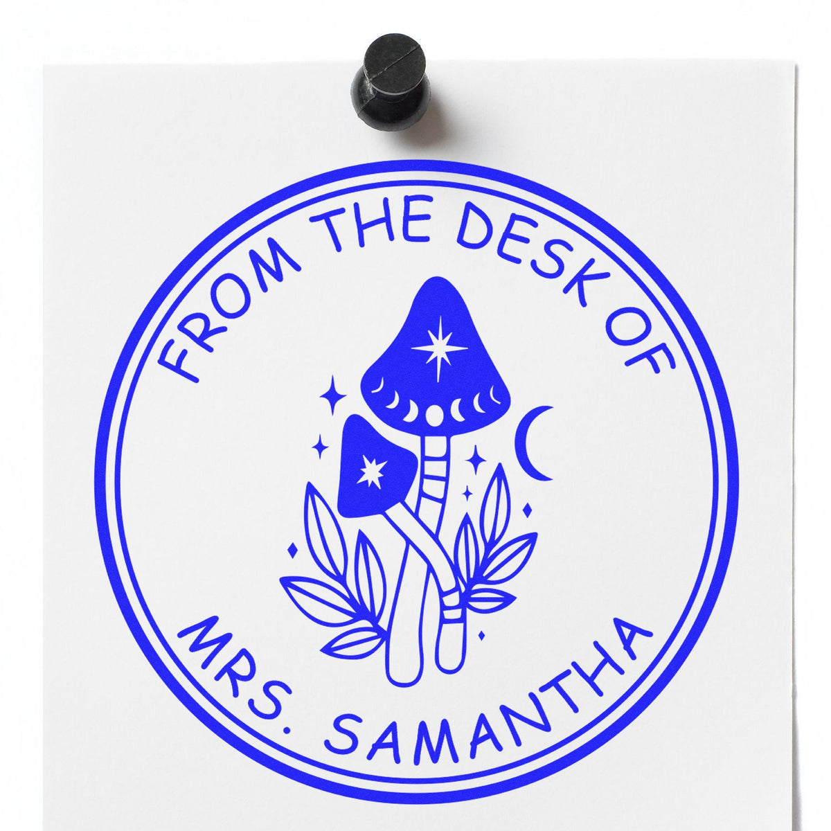 Blue circular stamp seal on white paper with mushrooms, moon and stars; black stamp handle above. From the desk of Mrs. Samantha.