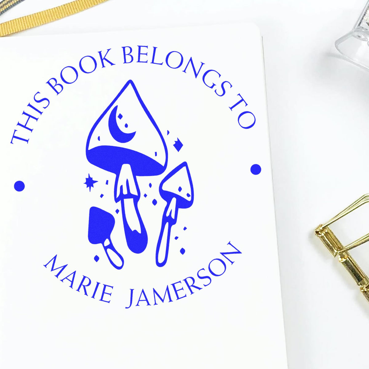 Blue mushroom bookplate stamp seal reading This Book Belongs to Marie Jamerson on white paper