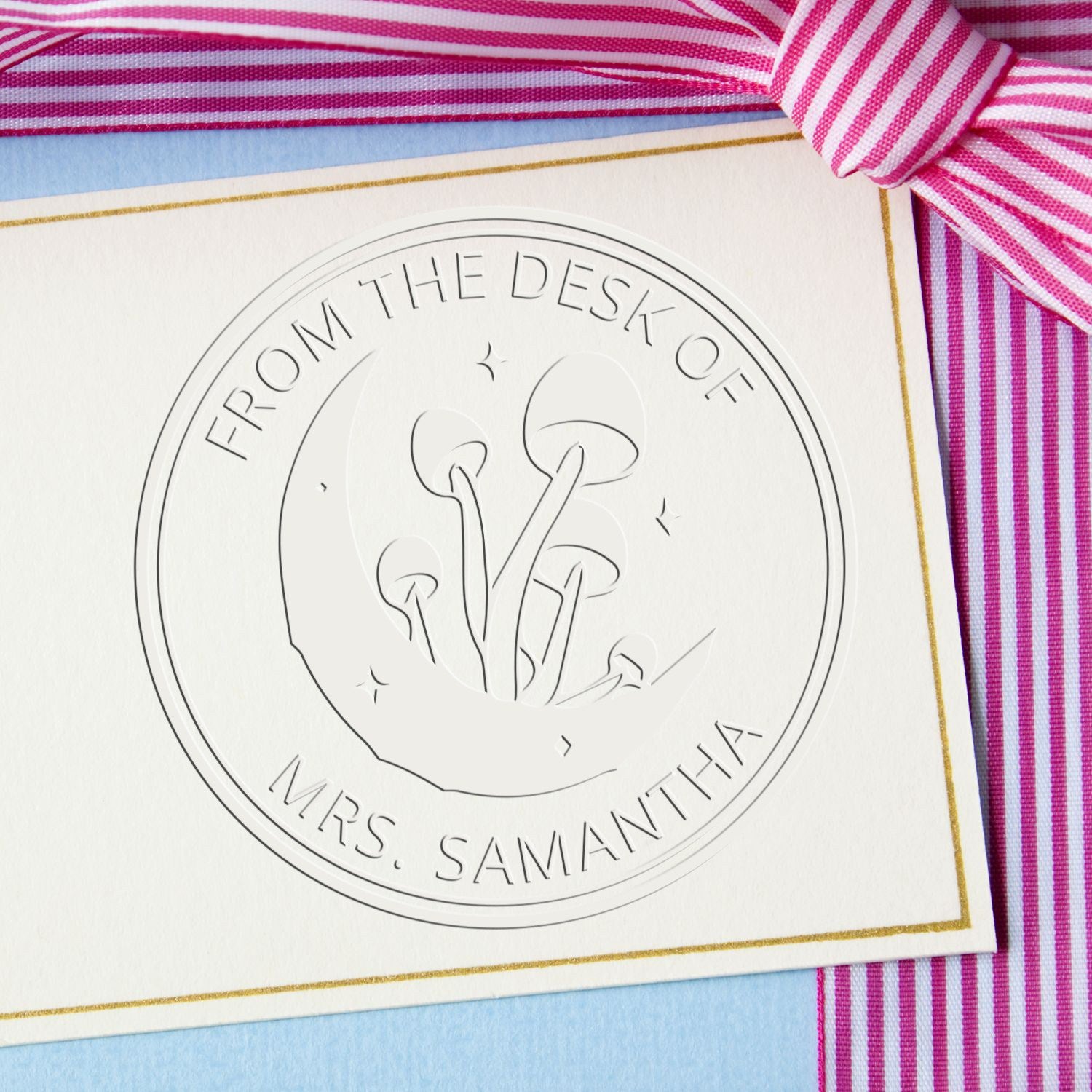 Embossed circular desk seal stamp on white card with gold border and pink striped ribbon; reads Mrs. Samantha.