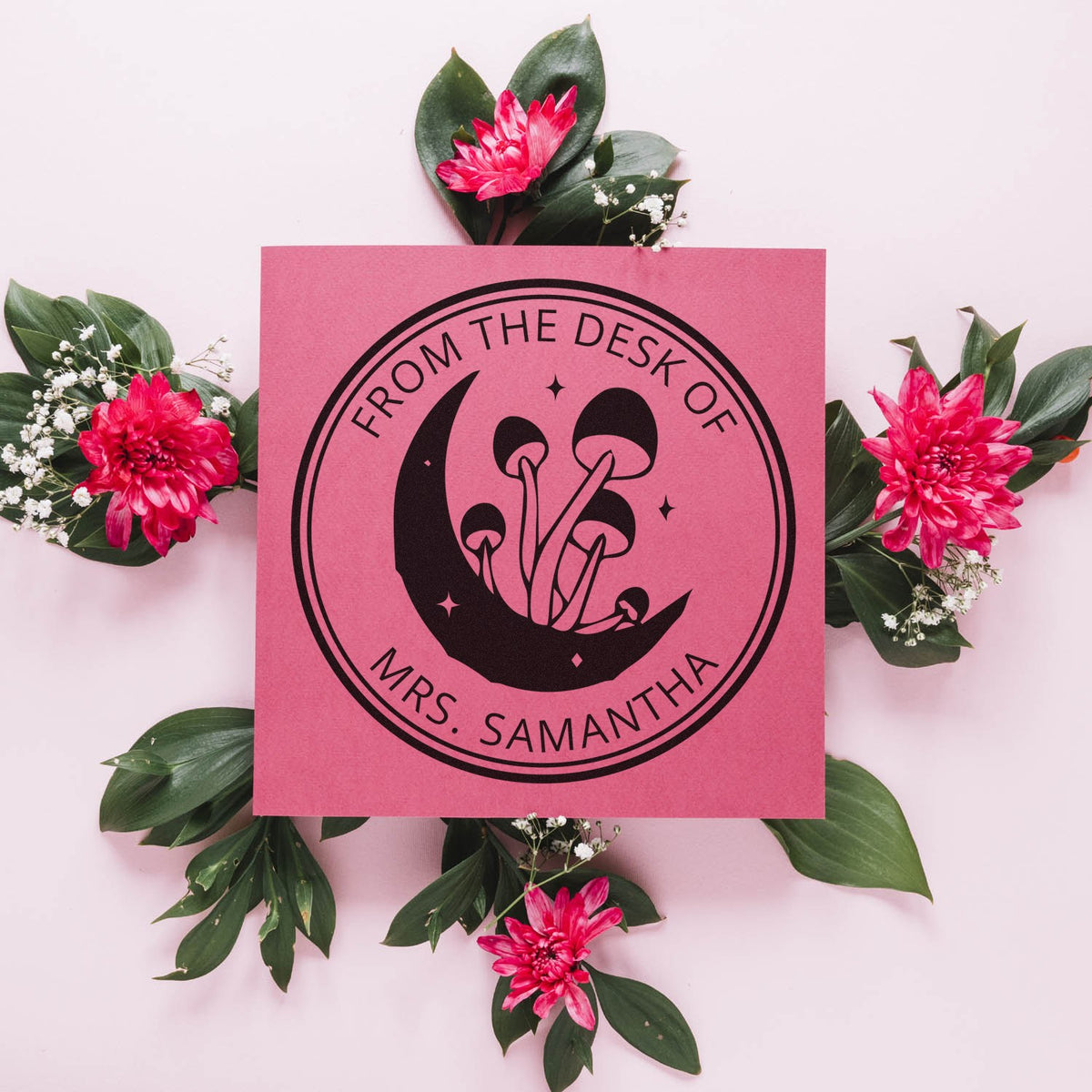 Pink custom stamp seal with black mushroom logo and From the Desk of Mrs. Samantha, framed by pink flowers and green leaves.