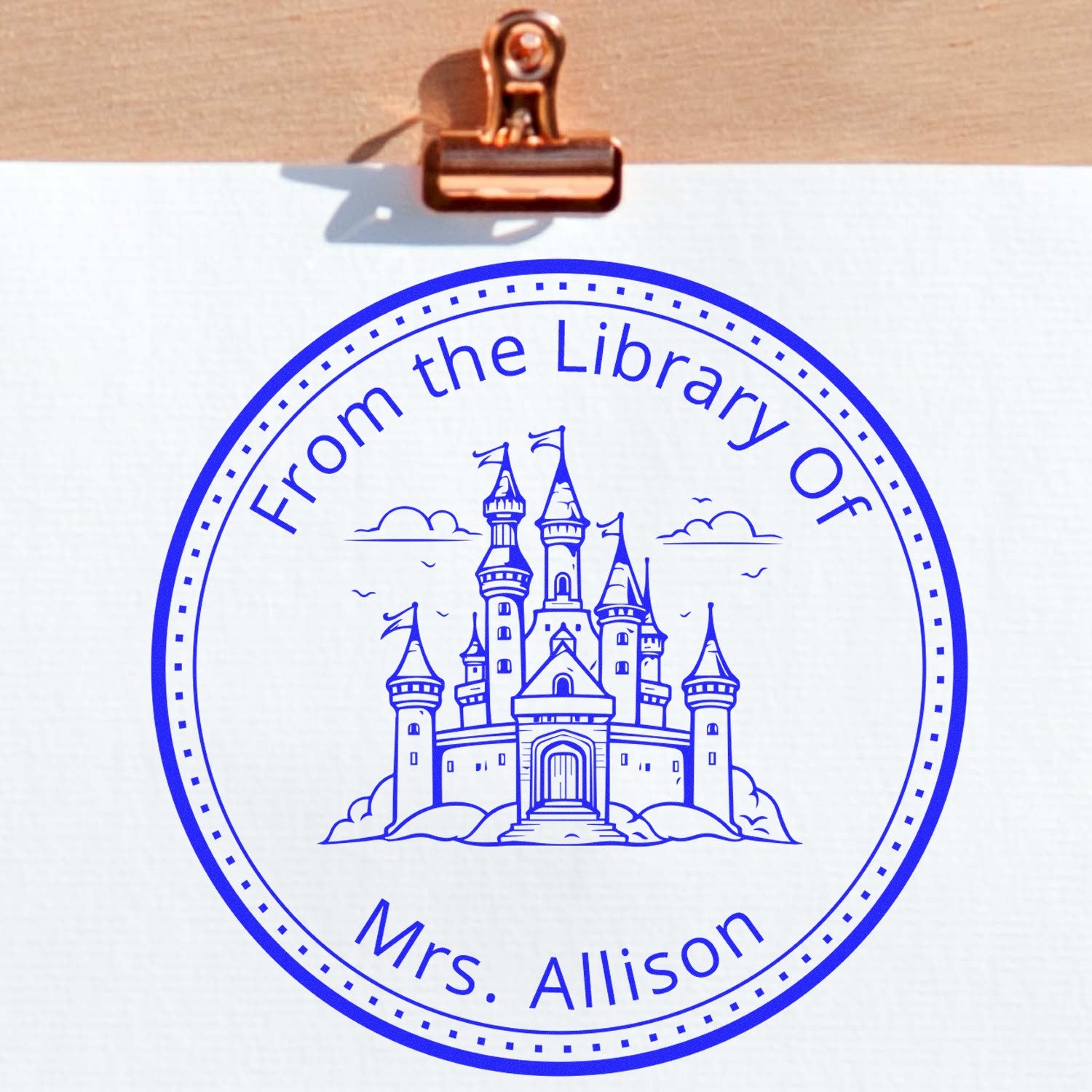 Blue custom library seal stamp on white paper, with castle graphic and From the Library Of Mrs. Allison text.