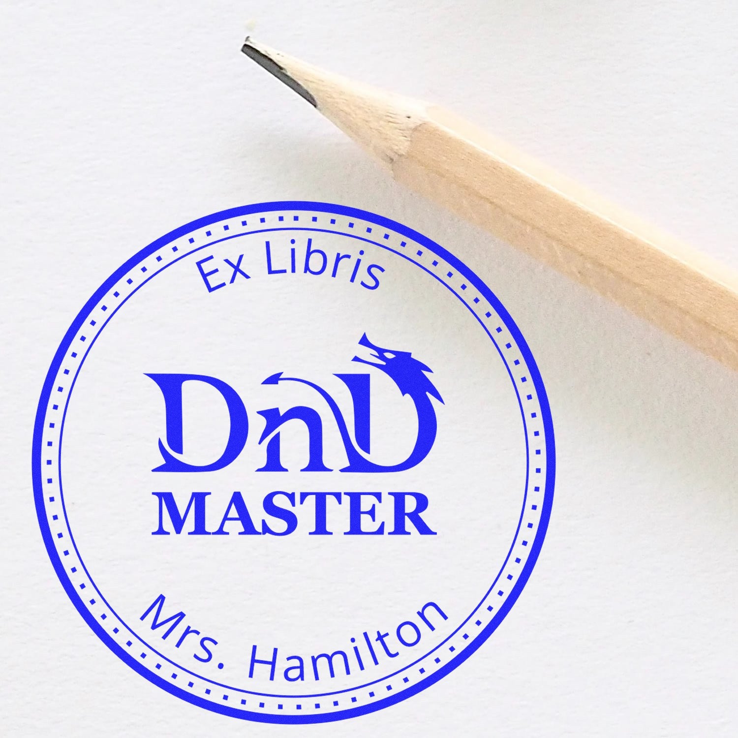 Blue circular Ex Libris DnD Master stamp and seal design with pencil tip on white paper, personalized for Mrs. Hamilton.