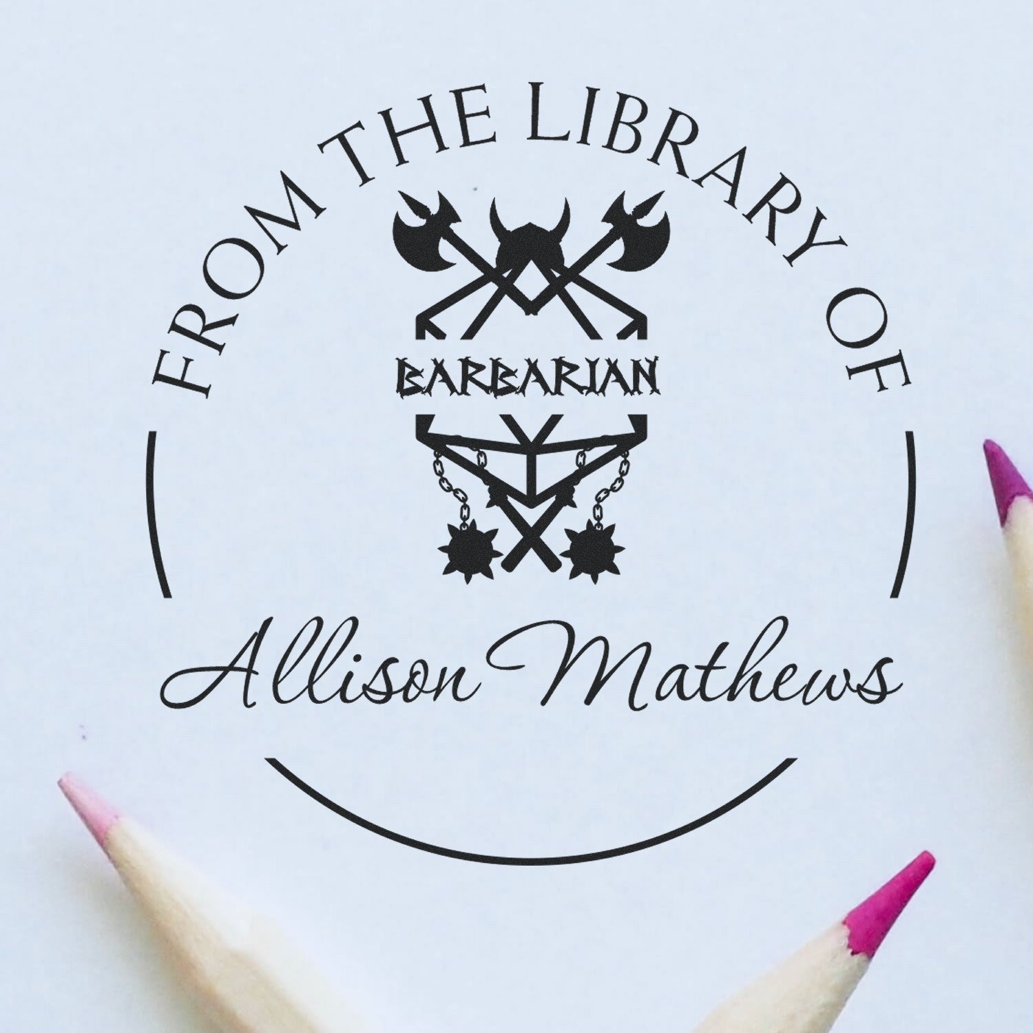 Black custom stamp and seal reading From the Library of Barbarian Allison Mathews with barbarian logo on white, pink pencil tips.