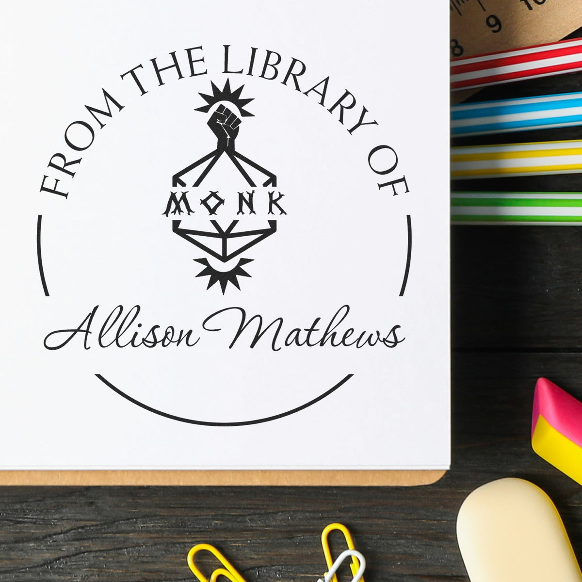 Custom black library stamp seal with “From the Library of Allison Mathews” on white paper, beside colorful stationery.